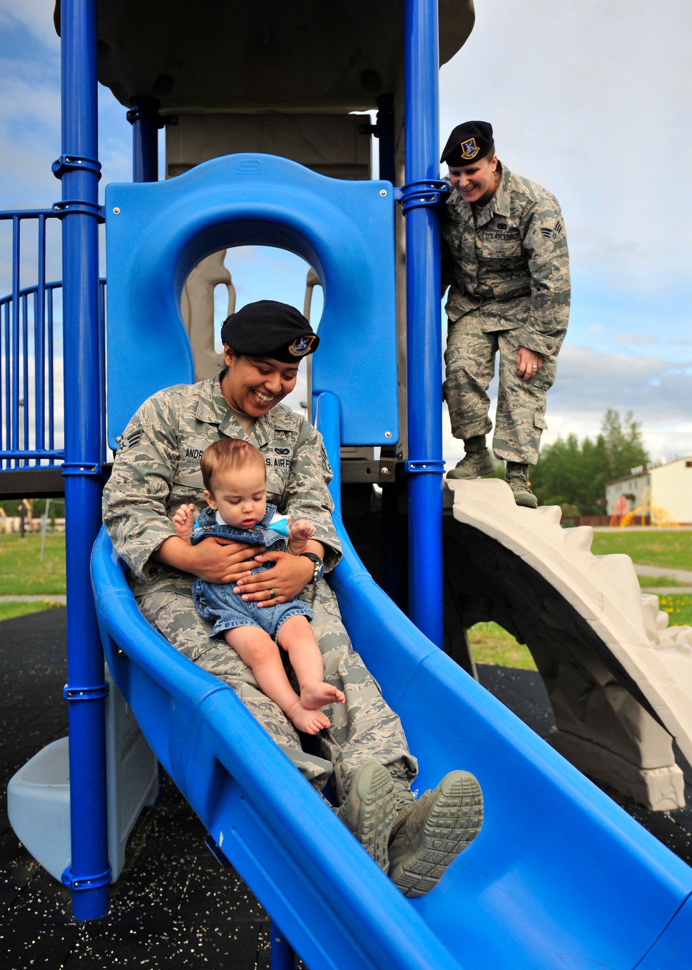 Senior Airmen Abigail, left, and Tori Andrade, 354th Security Forces Squadron members, play at a park with their son, Maximus, June 9, 2014, Eielson Air Force Base, Alaska. The Andrades married in Feb. 2013; they were the first married lesbian couple on base. (U.S. Air Force photo by Senior Airman Ashley Nicole Taylor/Released)