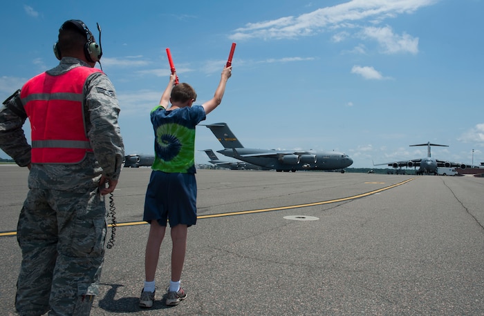An Airman assists Austin Miller, Col. Al Miller’s son, as he marshalls the aircraft his father flew for his final flight as the 437th Airlift Wing vice commander May 16, 2014, on the flightline at Joint Base Charleston, S.C. The final or "fini flight," is an aviation tradition in which aircrew members are met by their unit comrades, family and friends and then soaked with water. (U.S. Air Force photo/ Staff Sgt. William A. O’Brien)