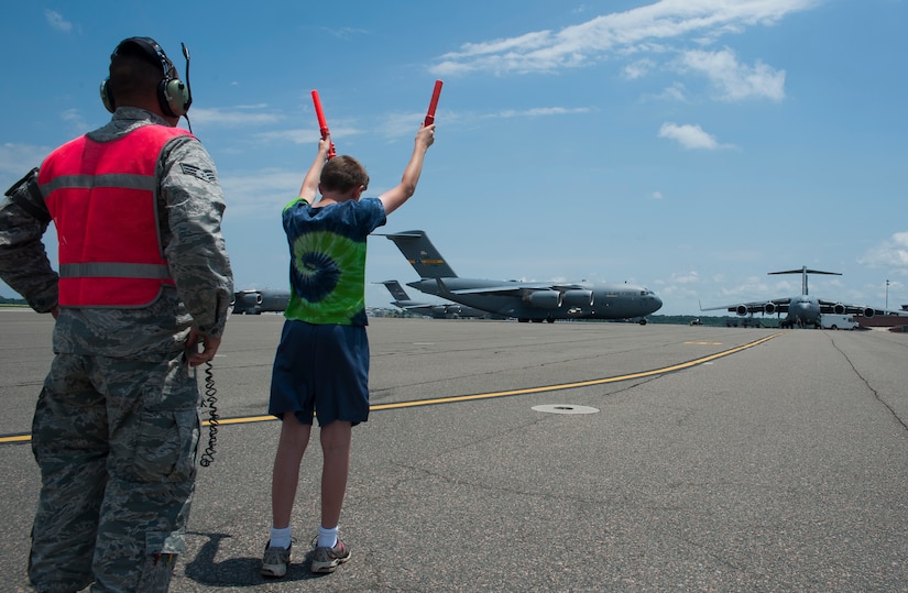 An Airman assists Austin Miller, Col. Al Miller’s son, as he marshalls the aircraft his father flew for his final flight as the 437th Airlift Wing vice commander May 16, 2014, on the flightline at Joint Base Charleston, S.C. The final or "fini flight," is an aviation tradition in which aircrew members are met by their unit comrades, family and friends and then soaked with water. (U.S. Air Force photo/ Staff Sgt. William A. O’Brien)