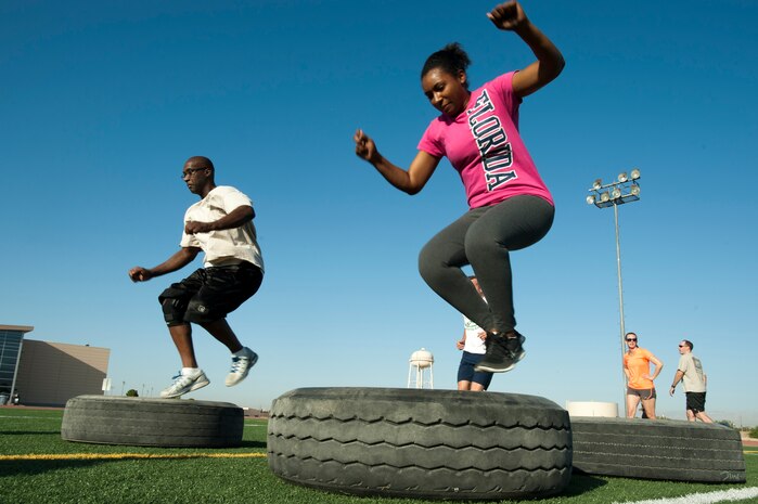 Participants jump through tires during a Warrior Trained Fitness exercise session at the Warrior Fitness Center June 12, 2014, at Nellis Air Force Base, Nev. The WTF exercise session was the last to be hosted by Missy Cornish, wife of Col. Barry Cornish, 99th Air Base Wing commander. (U.S. Air Force photo by Senior Airman Timothy Young)