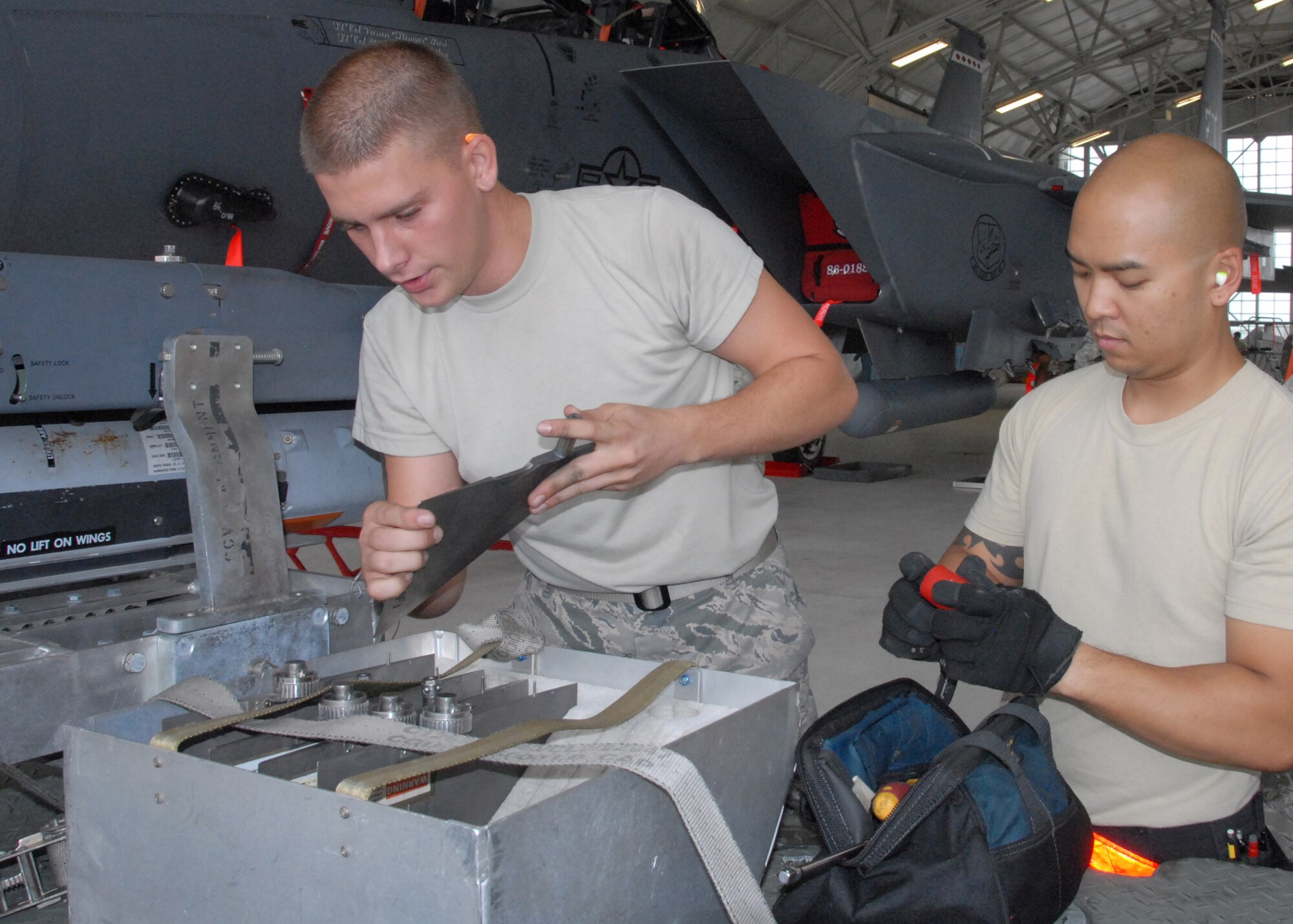 Airman 1st Class Luke Odom and Staff Sgt. Adrian Pamintuan, of the 96th Aircraft Maintenance Squadron Red, get ready to load munitions on an F-15 Strike Eagle during the 96th Maintenance Group's quarterly weapons load crew competition June 13 at Eglin Air Force Base, Fla. Along with Senior Airman Luis Cleveland, they defeated the Blue squadron team. (U.S. Air Force photo/Kevin Gaddie)