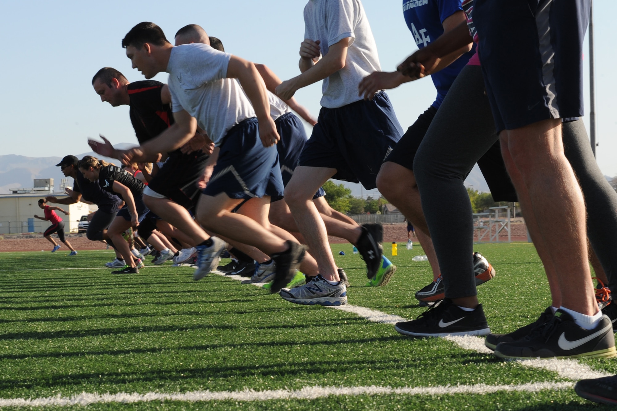 Members of the Nellis community sprint across the Warrior Fitness Center football field during a Warrior Trained Fitness workout June 12, 2014, at Nellis Air Force Base, Nev.  The WTF exercise session was the last to be hosted by Missy Cornish, wife of Col. Barry Cornish, 99th Air Base Wing commander. (U.S. Air Force photo by Tech. Sgt. Taylor Worley)