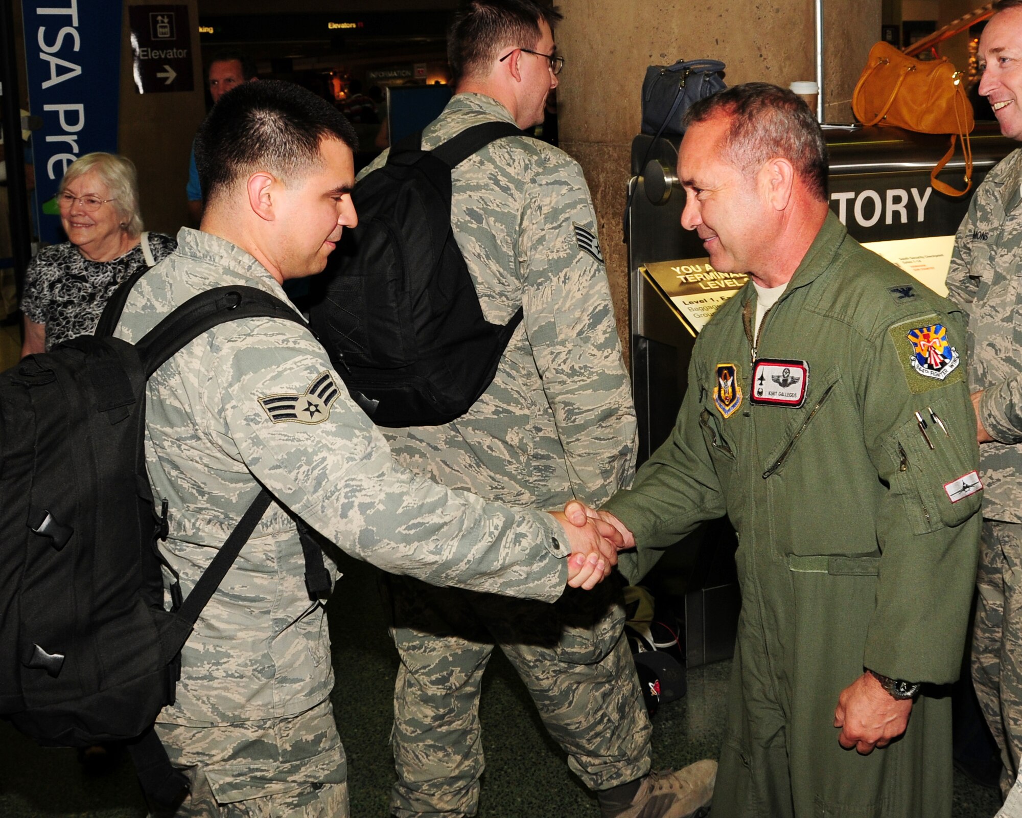Col. Kurt J. Gallegos, 944th Fighter Wing commander, shakes hands with Senior Airman James Alvarado, 944th Security Forces Squadron, and hands him a coin June 16 as he returns from a five month deployment overseas in support of the Transit Center at Manas. (U.S. Air Force photo taken by Tech. Sgt. Louis Vega Jr.)