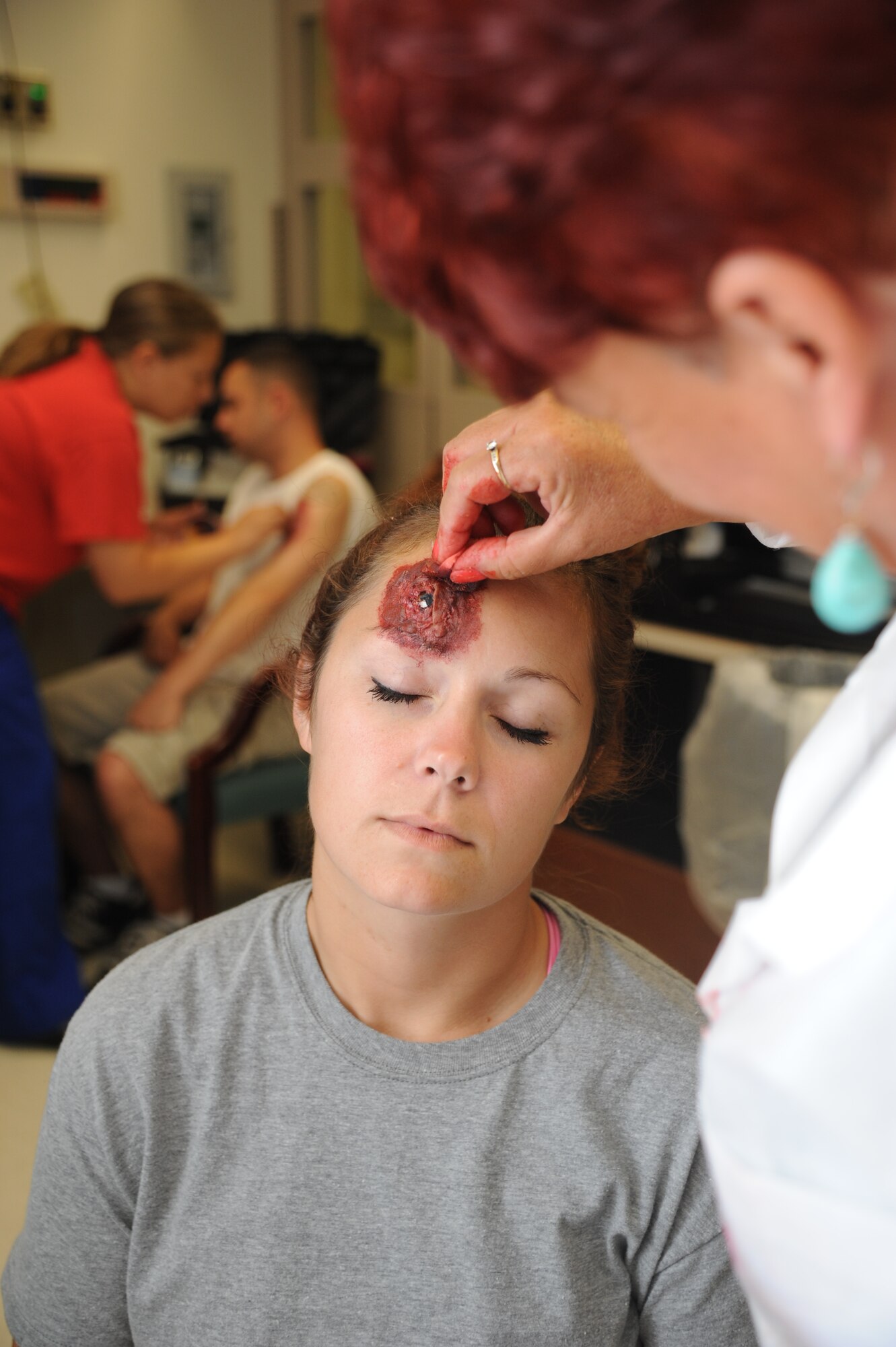 Dawn Hitchings, 81st Medical Group and exercise evaluation team member, applies moulage to Staff Sgt. Julia Berger, 81st Logistics Readiness Squadron, who portrayed an individual who was wounded during Keesler's active shooter exercise, June 11, 2014, at the Keesler Medical Center, Keesler Air Force Base, Miss.  An Air Force student simulated opening fire at the hospital after feeling he was wrongfully diagnosed.  The exercise tested the base's ability to respond to and recover from a mass casualty event.  (U.S. Air Force photo by Kemberly Groue)