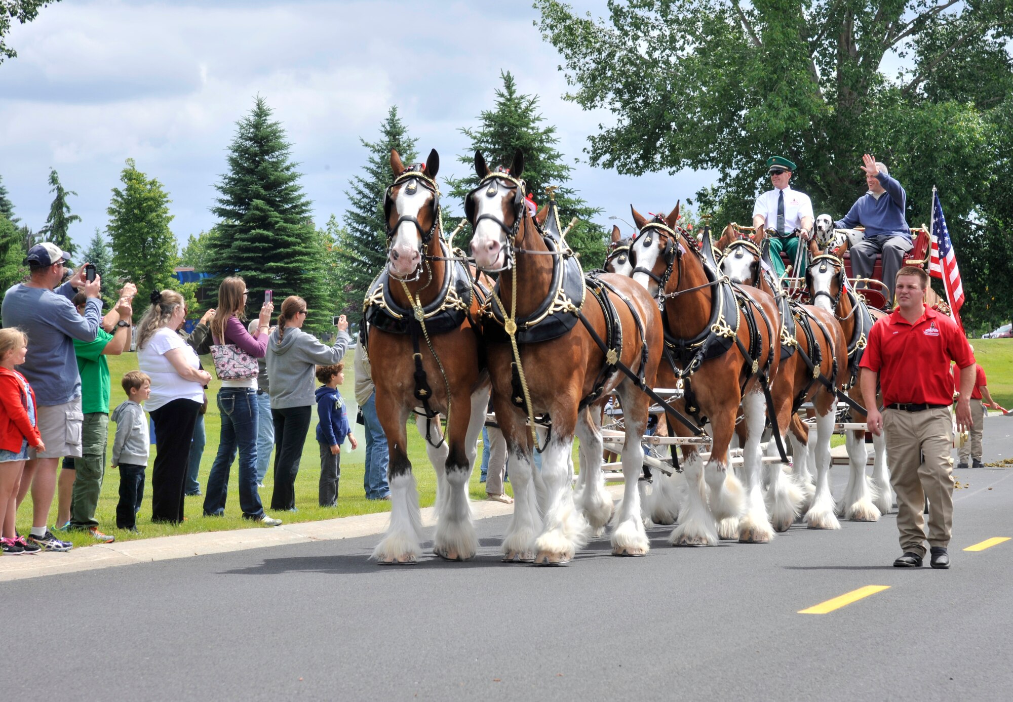 Col. Brian Newberry waves to the crowd as he rides by on the Anheuser-Busch Budweiser wagon at Fairchild Air Force Base, Wash., June 15, 2014. Eight of the Budweiser clydesdales were showcased at Fairchild this Father's Day for military families to see, as they travel across the country to different military bases. Newberry is the 92nd Air Refueling Wing commander. (U.S. Air Force photo by Senior Airman Mary O'Dell/Released)