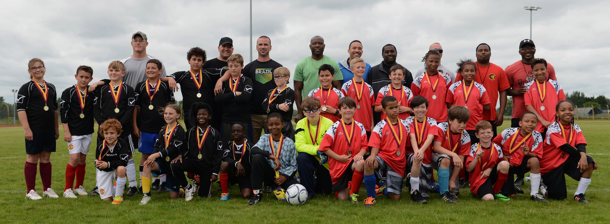 The Black Knights, left, the RAF Lakenheath Liberty Wing’s youth all-star soccer team, and the Red Dragons, Team Mildenhall’s youth all-star soccer team, pose with their medals after their match June 14, 2014, at Heritage Park on RAF Mildenhall, England. The Black Knights beat the Red Dragons after defeating them in two matches. (U.S. Air Force photo/Airman 1st Class Preston Webb/Released)