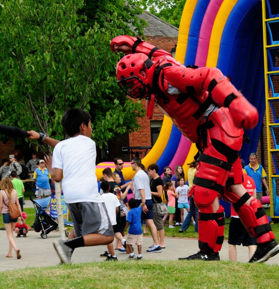 Jordan Ramirez, left, 10, son of U.S. Air Force Master Sgt. Jason Ramirez, 100th Civil Engineer Squadron Fire Department assistant chief of operations from Honolulu, whacks “Red Man,” U.S. Air Force Airman 1st Class Michael Spears, 100th Security Forces Squadron response force leader from Ashland, Ky., during a demonstration of baton training at the Marauder Melee June 13, 2014, on RAF Mildenhall, England. Team Mildenhall members participated in sporting events including a 5 km run, dodgeball, volleyball and tug-of-war. (U.S. Air Force photo/Karen Abeyasekere/Released)