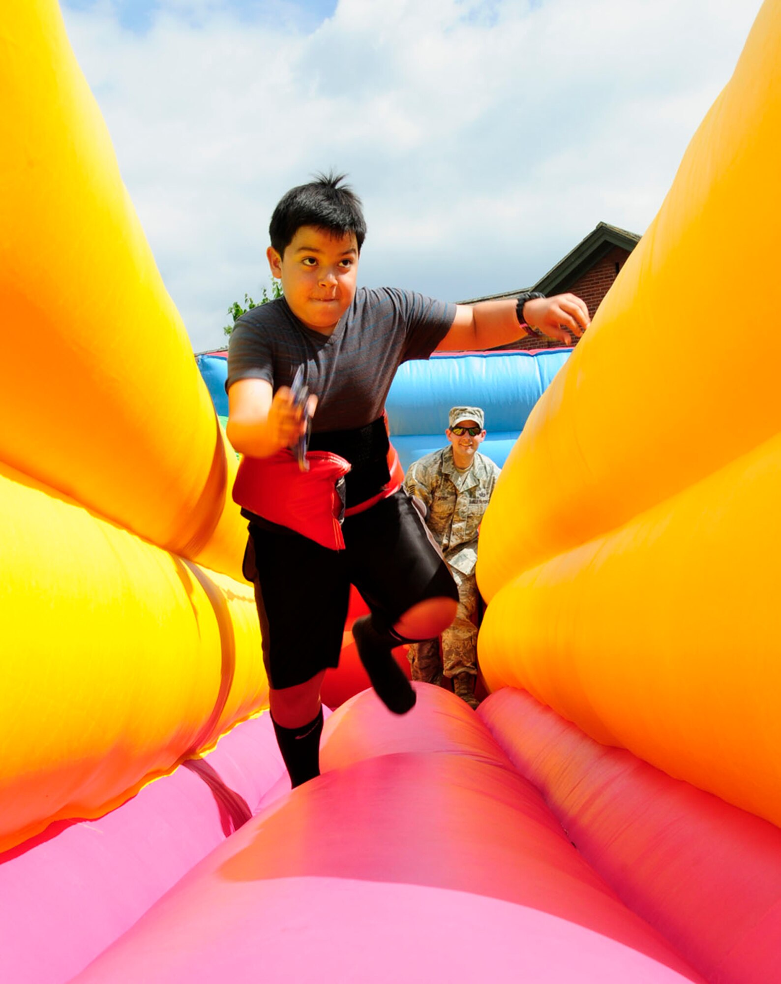 Jakob Nolde, 9, son of U.S. Air Force Tech. Sgt. Mark Nolde, 100th Force Support Squadron Military Personnel Section NCO in charge of customer support from San Antonio, prepares to place a beanbag on the inflatable wall during a bungee run June 13, 2014, at the Marauder Melee on RAF Mildenhall, England. Team Mildenhall members participated in sports including a 5 km run, dodgeball, volleyball and tug-of-war. The event was open to families in the afternoon and included activities such as water zorbing, bouncy castles, a mechanical bull and a petting zoo. (U.S. Air Force photo/Karen Abeyasekere/Released)