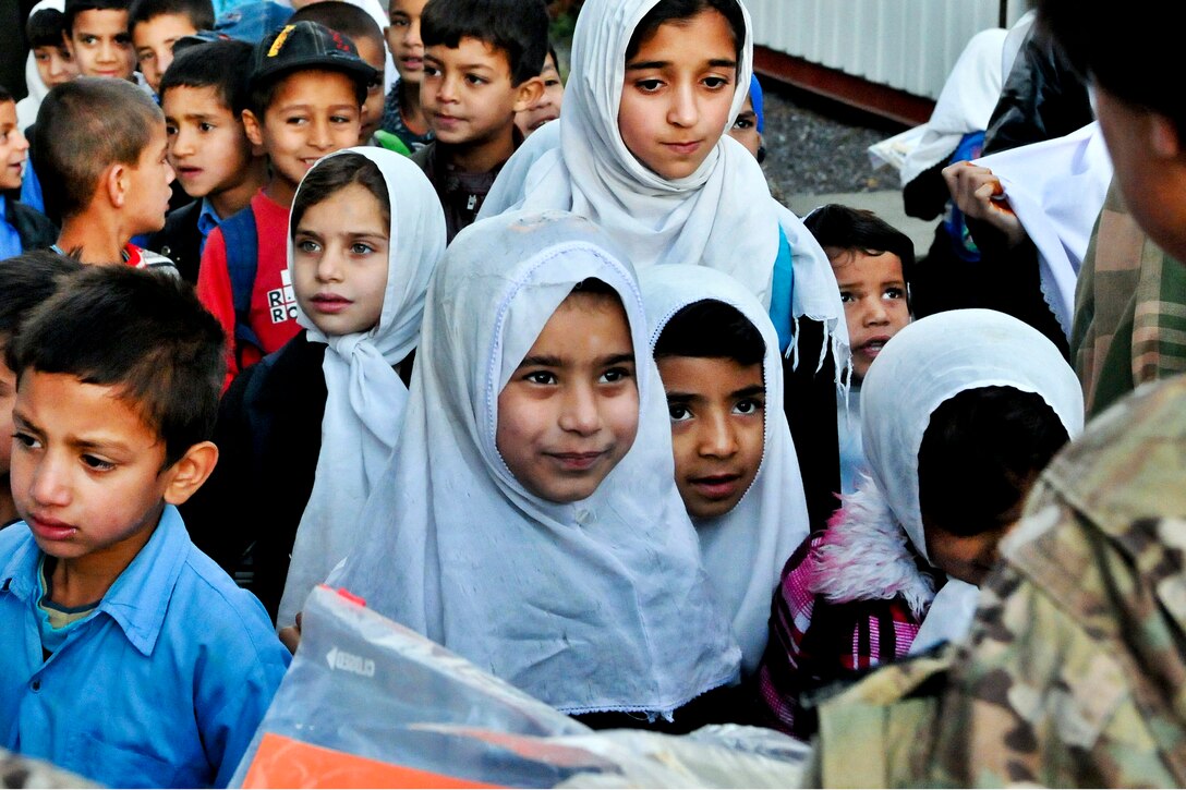 A U.S. service member distributes donated supplies to students at the Bibi Mahrow school in Kabul, Afghanistan, Oct. 12, 2011. The troops are assigned to the Medical Embedded Training Team, U.S. Forces Afghanistan, at the New Kabul Compound.  
