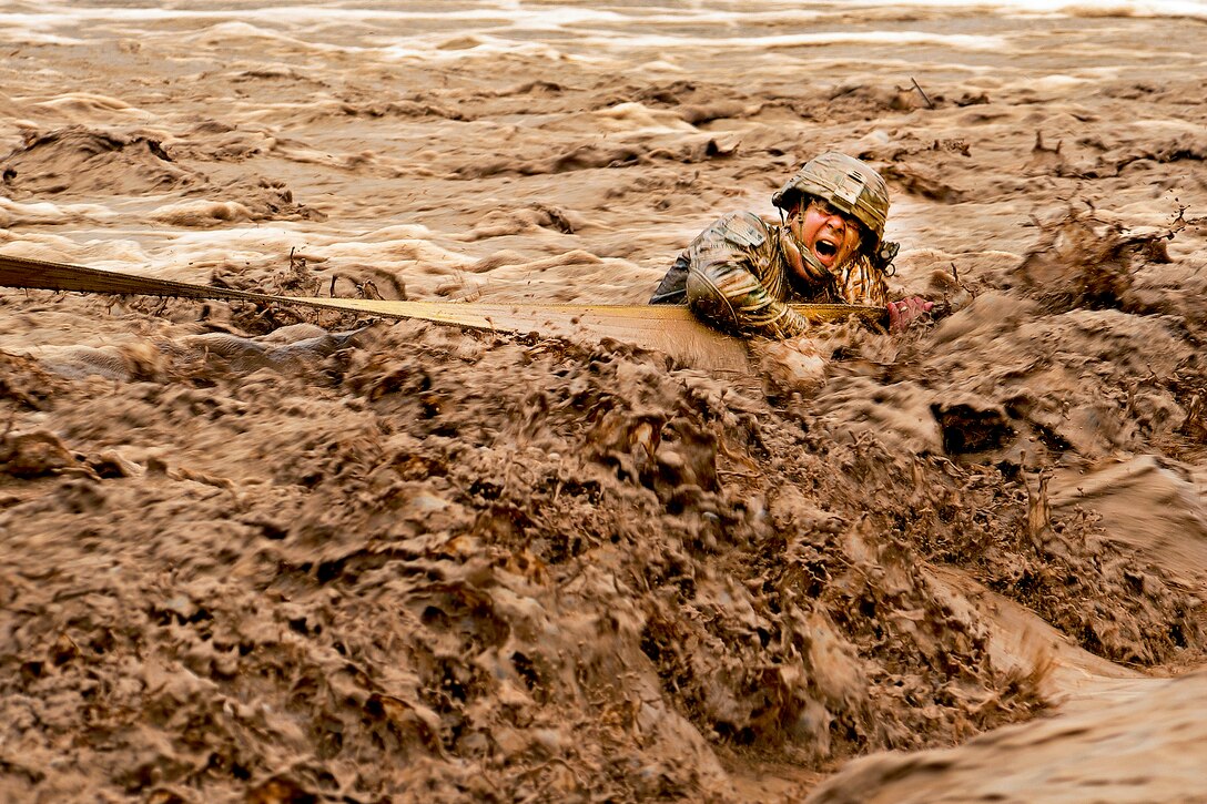 U.S. Army Staff Sgt. Patrick Reynolds fights racing water while holding on to a tow strap attached to an Afghan army vehicle stuck in the Lurah River in Afghanistan's Shinkai district, Oct. 12, 2011. Reynolds is a squad leader assigned to Provincial Reconstruction Team Zabul.  

