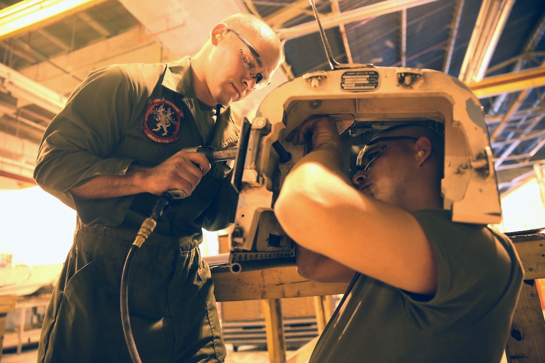 Lance Cpl. Lawrence Shouse (left) and Pfc. Jack Ramos perform technical directive maintenance on an ammo pack door in the metals shop within Marine Aviation Logistics Squadron 14 June 1, 2014. The squadron received earned a perfect grade in all 43 area of its recent Commanders of Naval Air Force inspection. Shouse and Ramos are both aircraft intermediate level structures mechanics with MALS-14.