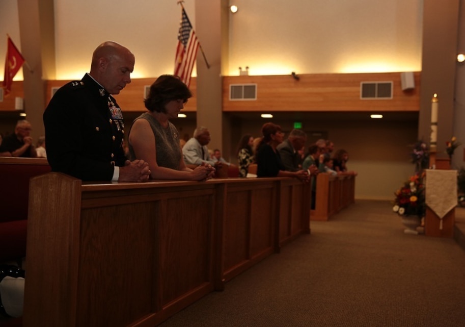 Maj, Gen. David H. Berger, Combat Center Commanding General, kneels in prayer during the memorial service for retired Marine Col. M.J. 'Mac' Dube at the base Catholic chapel, June 13, 2014. Dube enlisted in the Marine Corps in 1951 during the Korean War, and later commission in 1958.