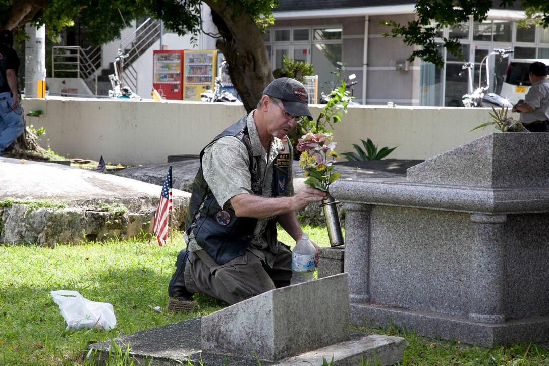 Retired U.S. Air Force Senior Master Sgt. Matthew Rossoni places flowers at the headstone holding the ashes of his in-laws May 26 during a visit by the American Legion Riders to the Tomari International Cemetery. The American Legion visited the cemetery in honor of Memorial Day and to pay respect to those who died in combat and family members laid to rest there. Rossoni is a native of San Francisco, Calif., and a program security manager with 18th Operations Group, 18th Wing. (U.S. Marine Corps photo by Lance Cpl. David N. Hersey/Released)