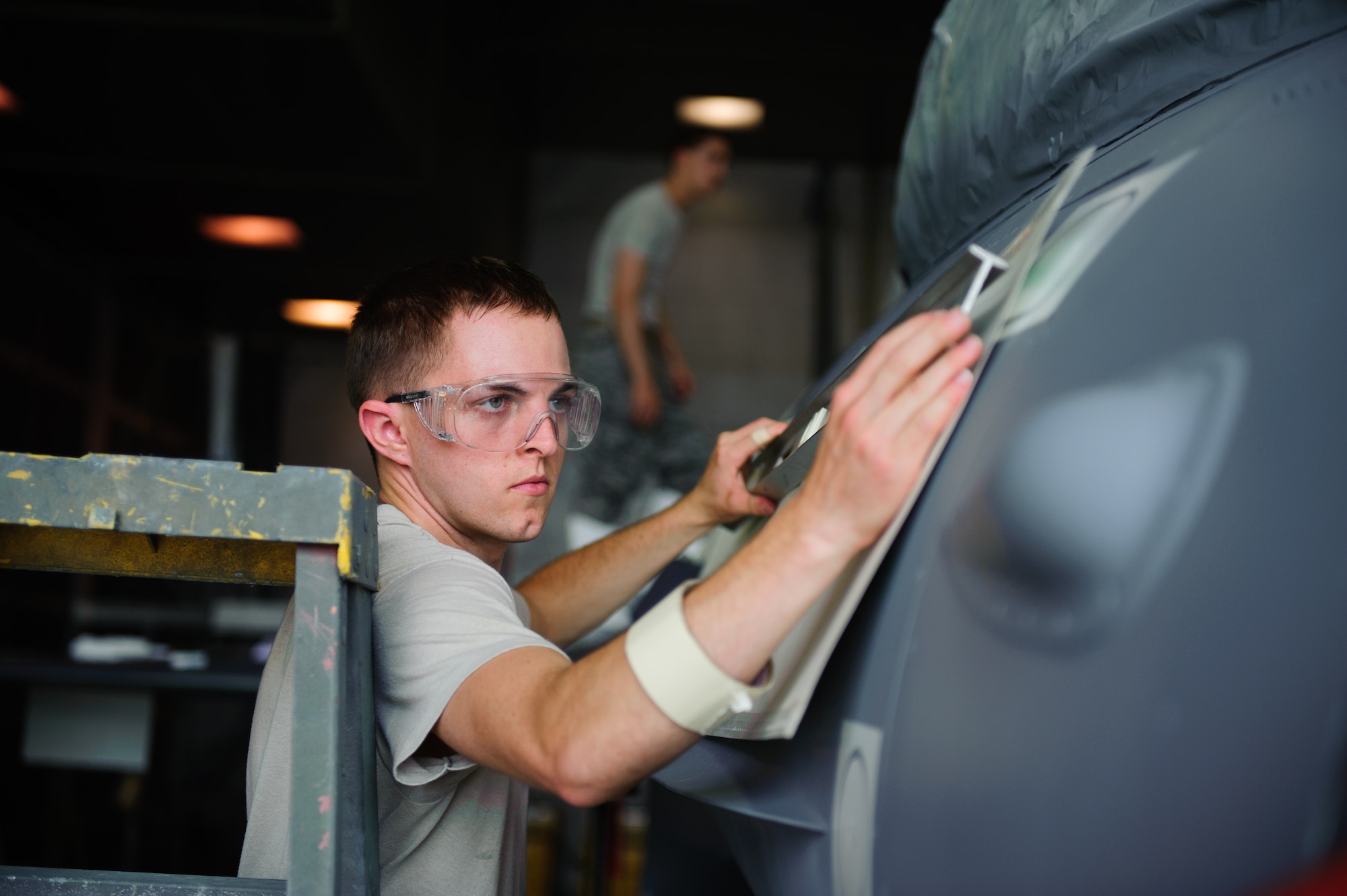 Senior Airman Joshua Kress, 8th Maintenance Squadron Aircraft Structural Maintenance journeyman, ensures the correct placement of a stencil during full-scale depot-level maintenance at Kunsan Air Base, Republic of Korea, June 11, 2014. The 8th MXG corrosion control section conducted a full wing-to-wing paint job in 10 work days, beating the expected 14 at a depot. (U.S. Air Force photo by Senior Airman Armando A. Schwier-Morales/Released)