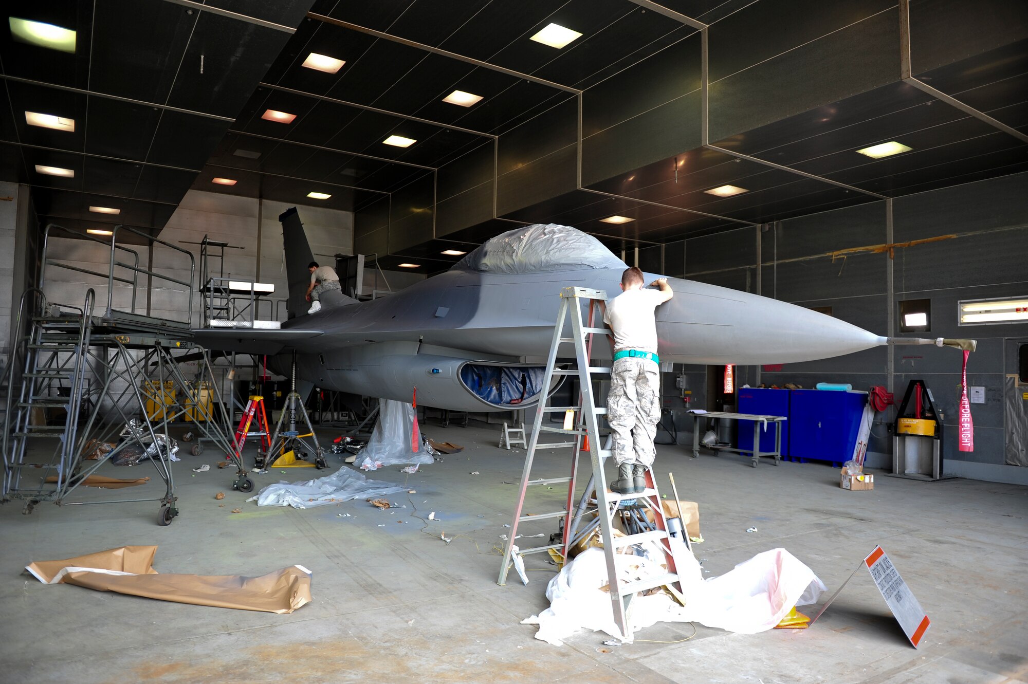 Airmen unmask an F-16 Fighting Falcon after it received its initial paint coats during a large-scale paint job at Kunsan Air Base, Republic of Korea, June 10, 2014. Masking an aircraft during painting allows Airmen to control the overspray of paint. Airmen from the 8th Maintenance Squadron corrosion control section conducted the first depot-level paint job at Kunsan in six years after a recent upgrade to their facility. (U.S. Air Force photo by Senior Airman Armando A. Schwier-Morales/Released)