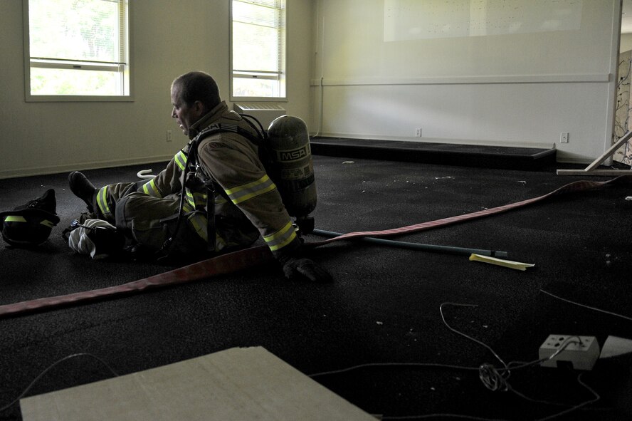 An airman catches his breath after completing a one hour scenario blind folded to find a trapped firefighter during Rapid Intervention Team training at Fairchild Air Force Base, Washington, June 13, 2014. Fairchild hosted 14 Airmen from seven separate fire stations throughout the Air Force Space Command. Teams of two train together in buildings compiled with scenarios that help mimic the real life possibilities of being trapped, injured or lost. (U.S. Air Force photo/Staff Sgt. Alexandre Montes)