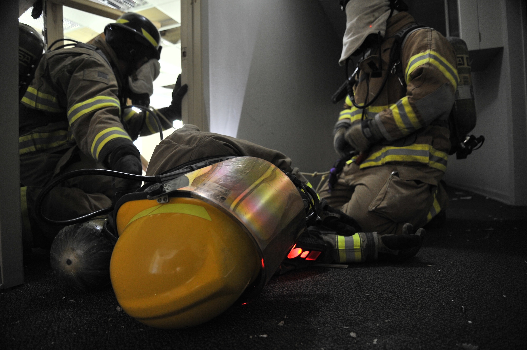 Trainees attempt to extract a trapped firefighter during Rapid Intervention Team training at Fairchild Air Force Base, Wash., June 13, 2014. Fairchild hosted 14 Airmen from seven separate Fire Stations throughout the Air Force Space Command. Teams of two train together in buildings compiled with scenarios that help mimic the real life possibilities of being trapped, injured or lost. (U.S. Air Force photo by Staff Sgt. Alexandre Montes/Released)