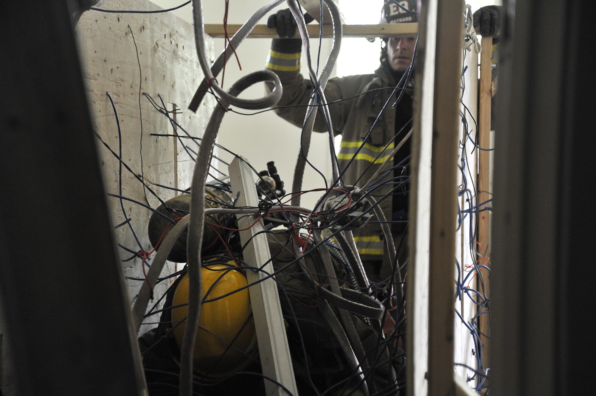 Kristofer Maynard, 92nd Civil Engineer Squadron firefighter, instructs a student through a simulated fallen ceiling obstacle during Rapid Intervention Team training at Fairchild Air Force Base, Wash., June 13, 2014. Fairchild hosted 14 Airmen from seven separate Fire Stations throughout the Air Force Space Command. Teams of two train together in buildings compiled with scenarios that help mimic the real life possibilities of being trapped, injured or lost. (U.S. Air Force photo by Staff Sgt. Alexandre Montes/Released)