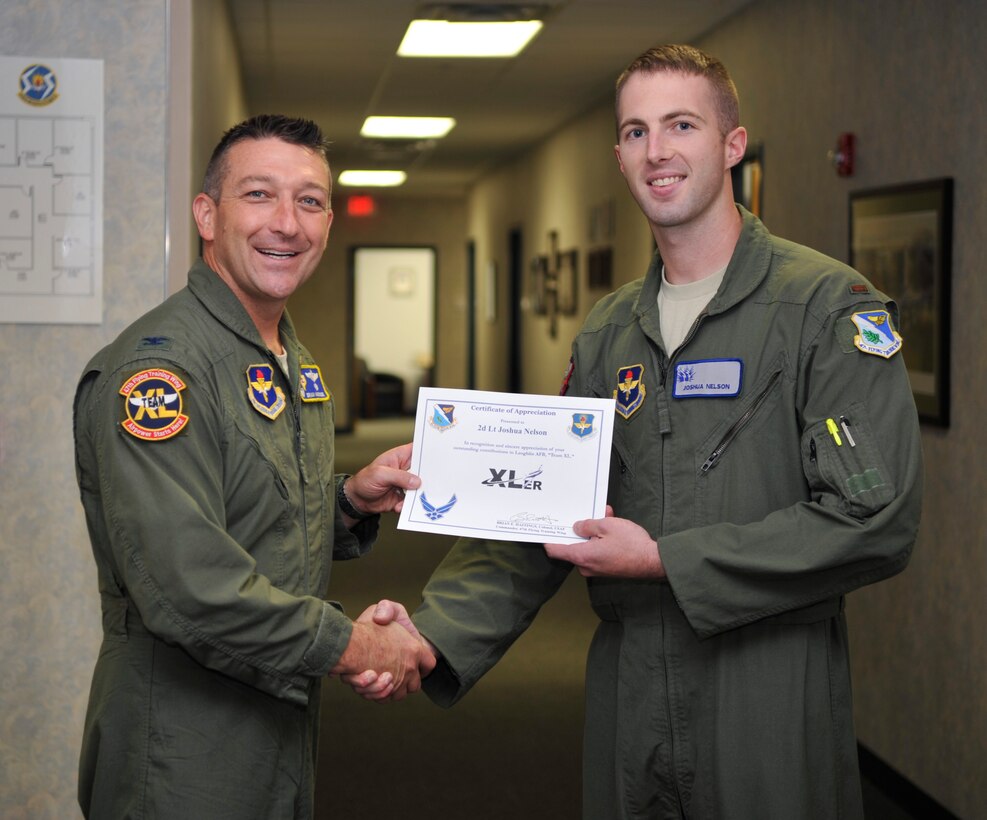 Second Lt. Joshua Nelson, right, 47th Student Squadron student pilot, poses with Col. Brian Hastings, left, 47th Flying Training Wing commander, after being presented the XLer of the week award here June 18, 2014. The XLer is a weekly award chosen by wing leadership and given to those who consistently make outstanding contributions to their unit and Laughlin. (U.S. Air Force photo by Airman 1st Class Jimmie D. Pike)(Released)