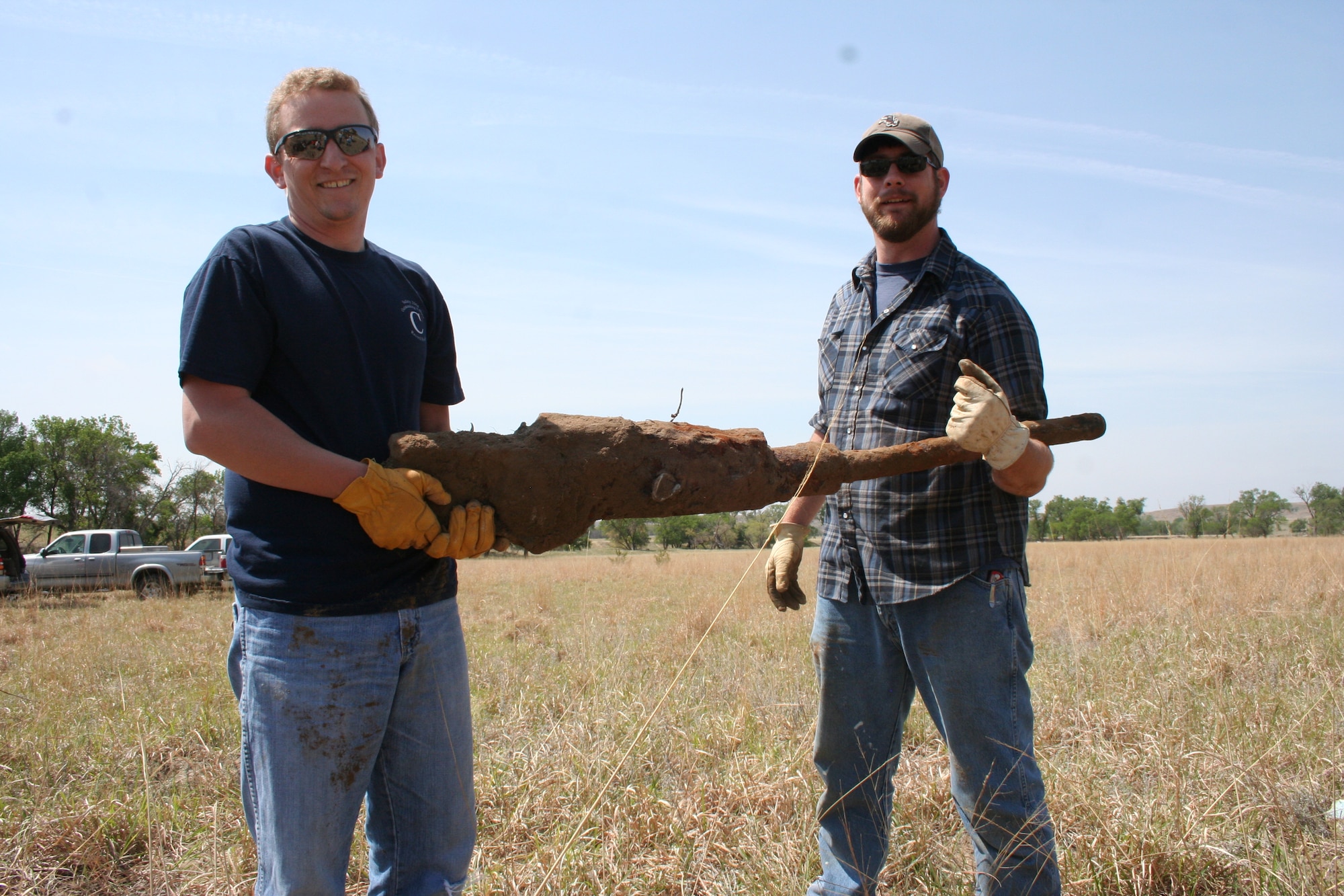 Two workers pose with a rusted Browning M2 machine gun, May 18, 2014, in Russell, Kan. The gun was part of a B-29 Superfortress that crash landed in the area back in 1945. The gun will be donated by the men to a local museum. (Courtesy Photo)