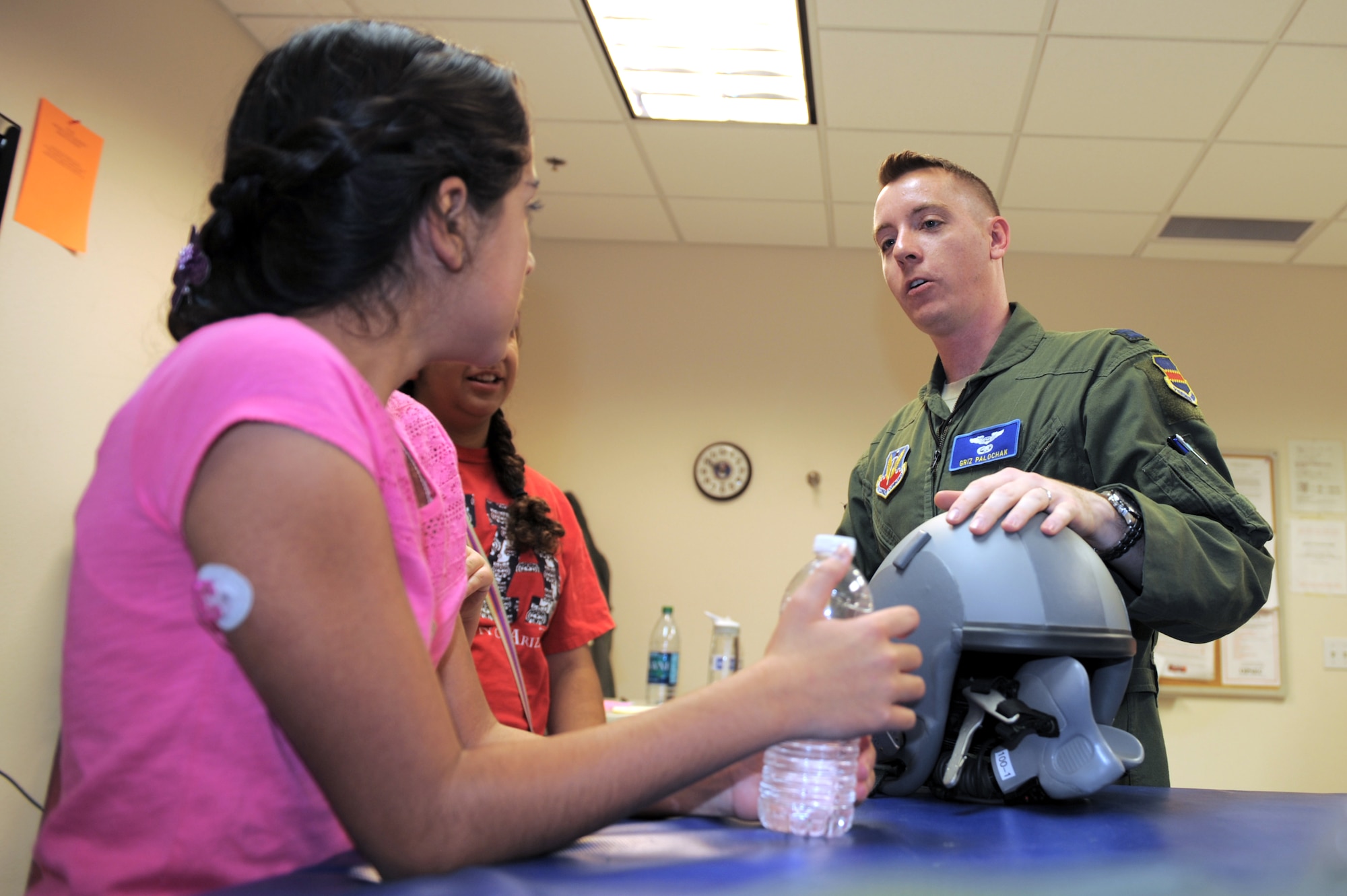 U.S. Air Force Capt. Joshua Palochak, 41st Electronic Combat Squadron weapons and tactics flight commander, explains the functions of a flight helmet to Christina Tellez, University of Arizona Steele Children?s Research Center patient, during a base tour at Davis-Monthan Air Force Base, Ariz., June 12, 2014. Steele Children?s Research Center specializes in better treatments for pediatric illnesses such as Type 1 diabetes, cancer and cystic fibrosis. (U.S. Air Force Photo by Airman 1st Class Chris Drzazgowski/Released) 