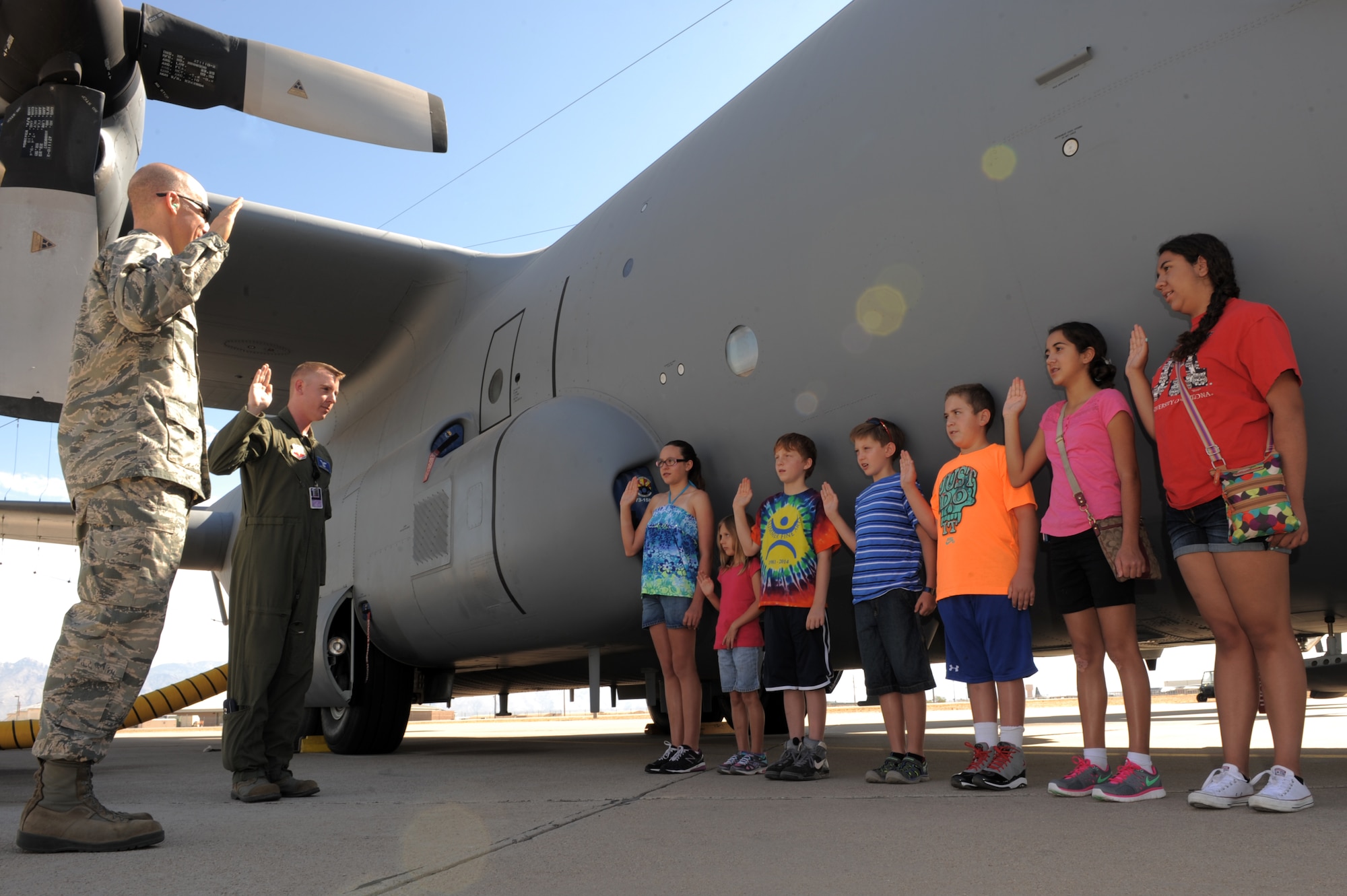 Patients from the University of Arizona Steele Children?s Research Center in Tucson, Ariz., recite the Oath of Enlistment administered by Lt. Col. Daniel Hendrix, 41st Electronic Combat Squadron commander, and Capt. Joshua Palochak, 41st ECS weapons and tactics flight commander, outside of a EC-130H static display during a base tour at Davis-Monthan Air Force Base, Ariz., June 12, 2014. The recital solidified the patients? as members of the 41st ECS ?Scorpions.? (U.S. Air Force photo by Airman 1st Class Chris Drzazgowski/Released) 