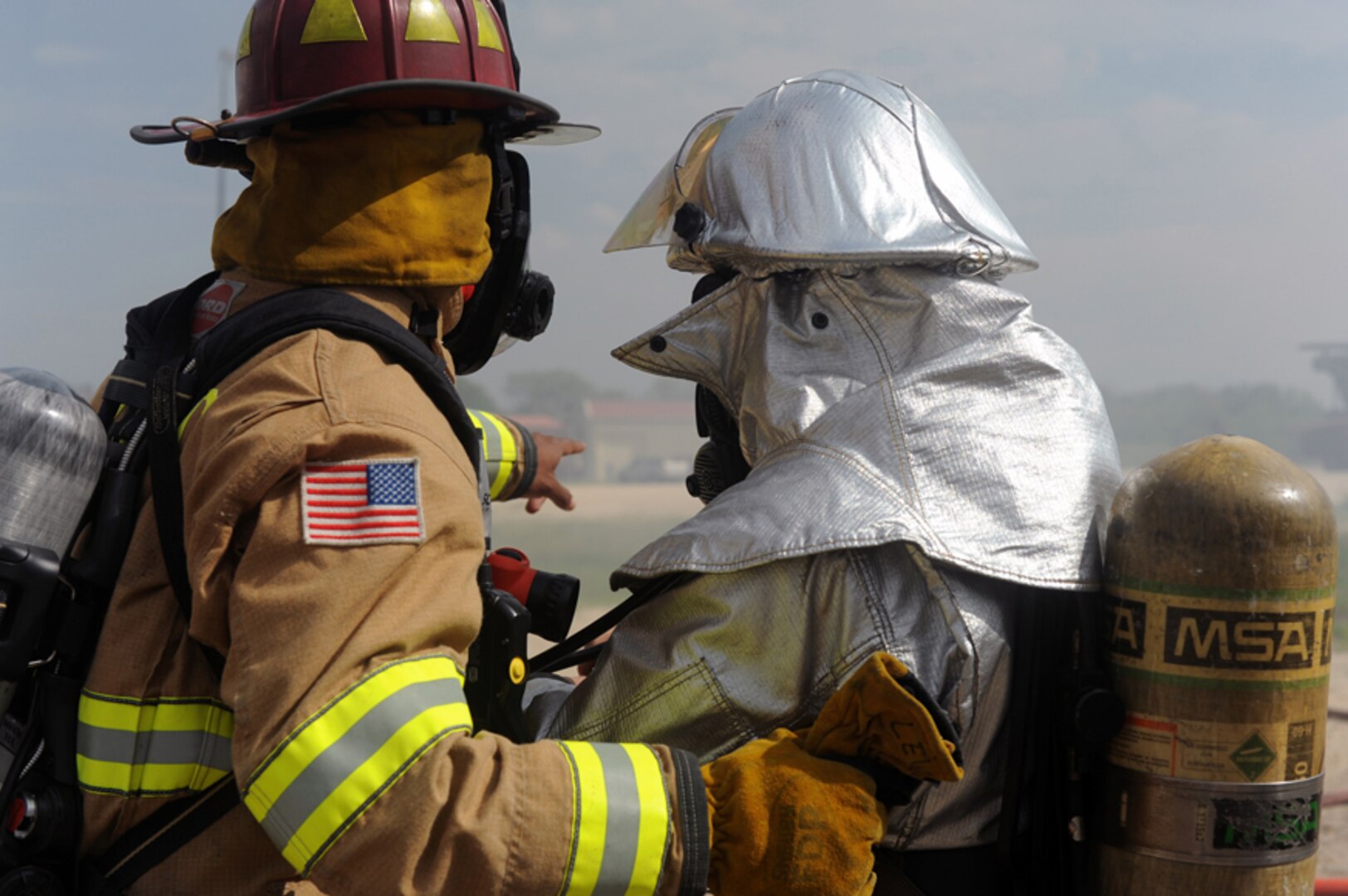 A Universal City Fire Department firefighter directs a 502nd Civil Engineer Squadron firefighter June 12 during structural live-fire training. (U.S. Air Force photo by Desiree Palacios)