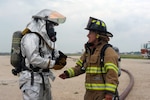Staff Sgt. Erik Chittick (left), 502nd Civil Engineer Squadron firefighter, speaks with Marla Jendrusch, Universal City Fire Department firefighter, during structural live-fire training June 12 at Joint Base San Antonio-Randolph. (U.S. Air Force photo by Desiree Palacios)