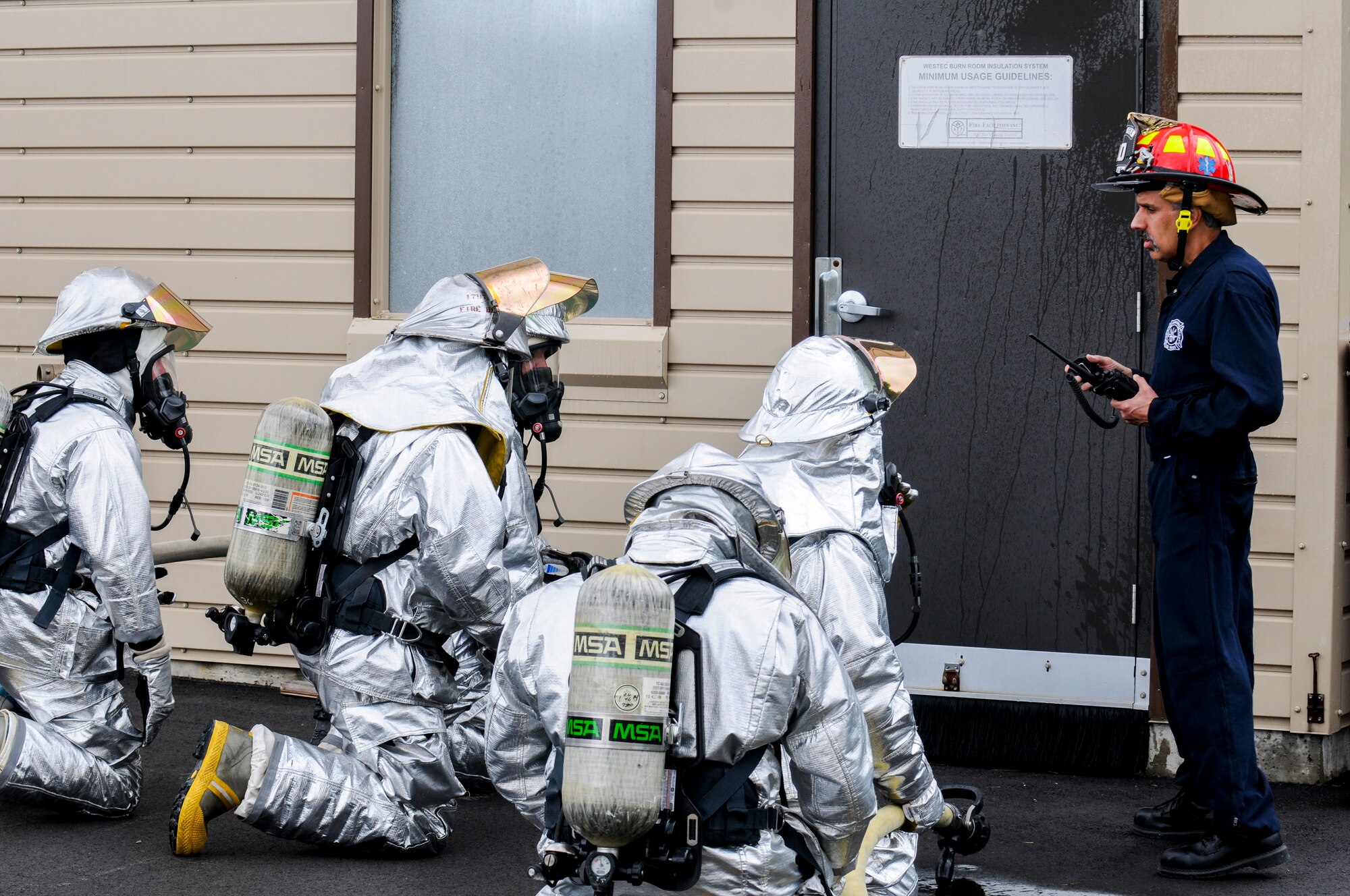 Dean Stanley (right), a Youngstown Air Reserve Station firefighter, instructs firefighters from the 179th Airlift Wing, Mansfield Lahm Air National Guard Base, Ohio, before they enter structural fire simulation building for training here, June 18, 2014. More than 20 Mansfield firefighters came to Youngstown June 17-18 to complete annual training at the fire training area. The training included internal and external firefighting using an ignitable mock aircraft and firefighting inside a structural fire simulation building. U.S. Air Force photo/Eric M. White.