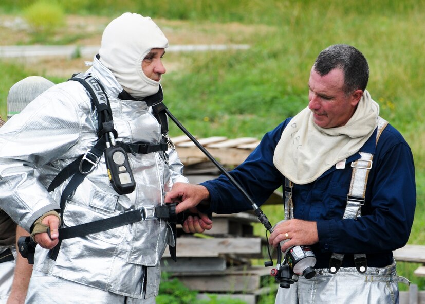 Firefighters from the 179th Airlift Wing, Mansfield Lahm Air National Guard Base, Ohio, help each other don firefighting gear prior to entering a training facility here, June 18, 2014. More than 20 Mansfield firefighters came to Youngstown June 17-18 to complete annual training at the fire training area. The training included internal and external aircraft firefighting using an ignitable mock aircraft and firefighting inside a structural fire simulation building. U.S. Air Force photo/Eric M. White.