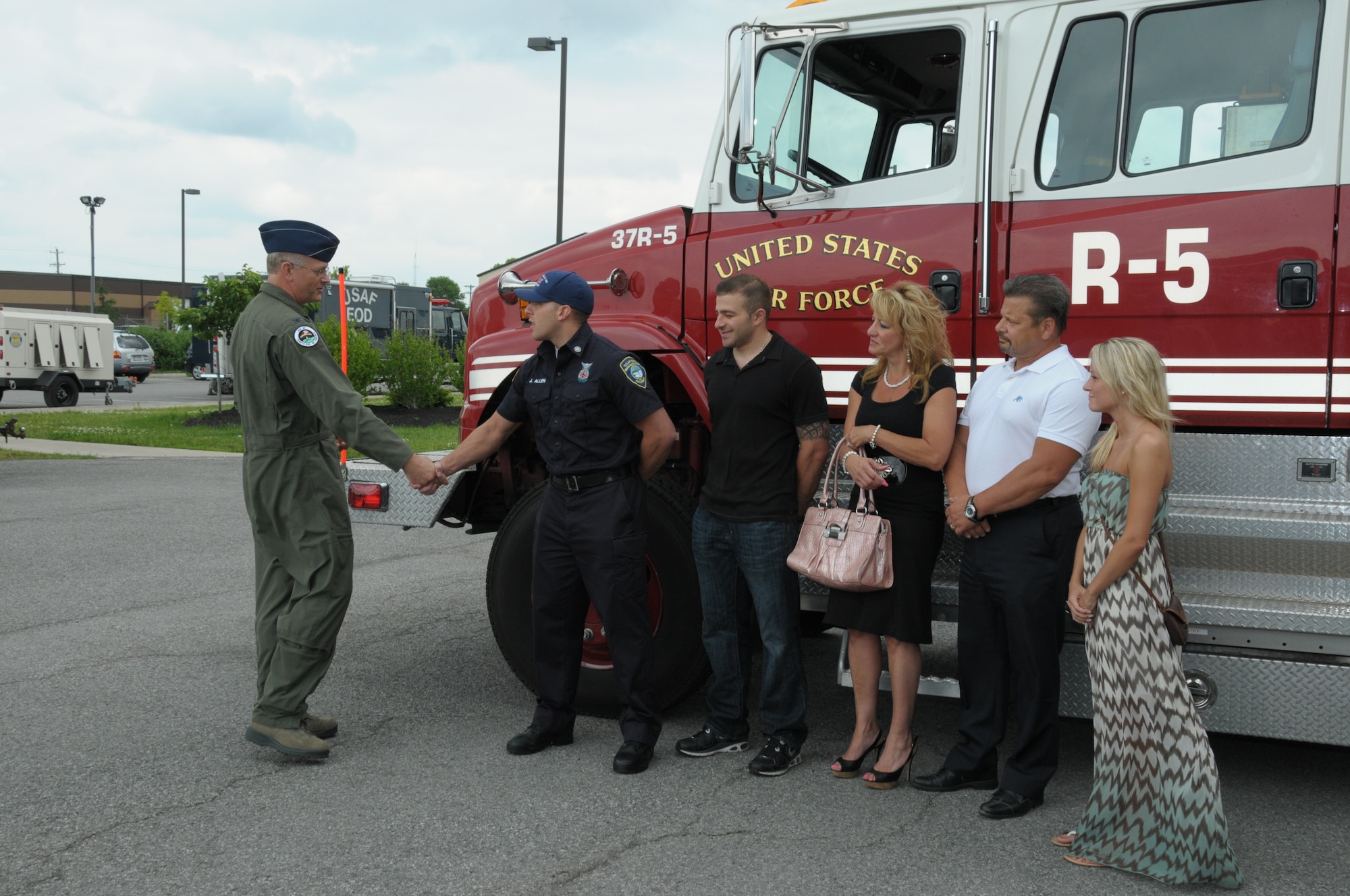 Col. Steven Parker (Left), 914th Airlift Wing Commander, presents Joseph Allen, 914th Fire Emergency Services Department of Defense civilian and Air Force Reserve Firefighter/Emergency Medical Technician, with a commander's coin while Allen’s family members look on at the Niagara Falls Air Reserve Station, N.Y. on June 12, 2014. The coin was presented to Allen who responded and treated a woman involved in a serious auto accident. (U.S. Air Force Photo by Peter Borys) 