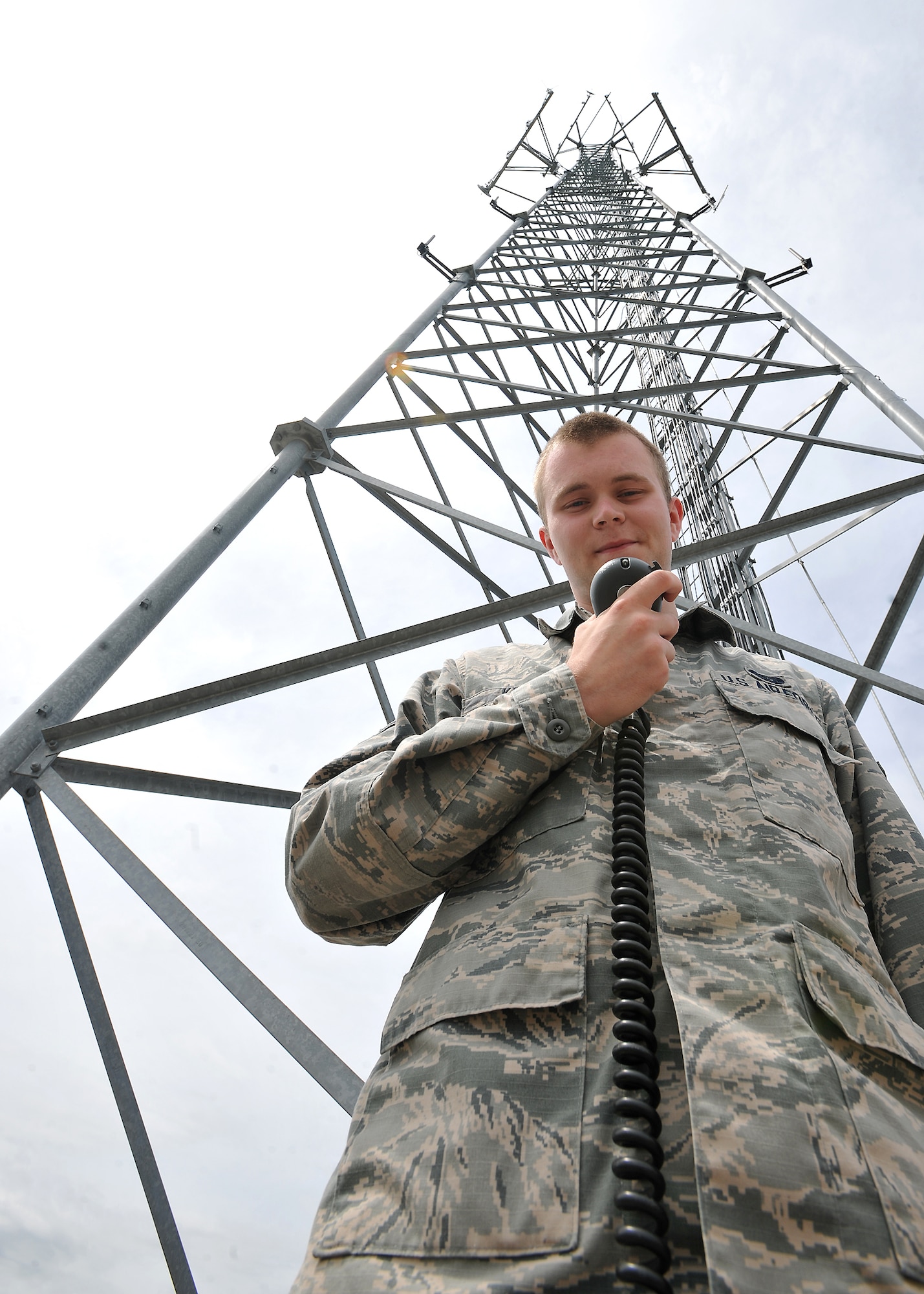 With a hand-held microphone in his grips, Airman Anthony Kelly, a 319th Communications Squadron high-frequency global communication system operator, poses in front of a radio tower on Grand Forks Air Force Base, N.D., June 16, 2014. Kelly a native of Worcester, Mass., was named Warrior of the Week for the third week of June 2014. (U.S. Air Force photo/Senior Airman Xavier Navarro)
