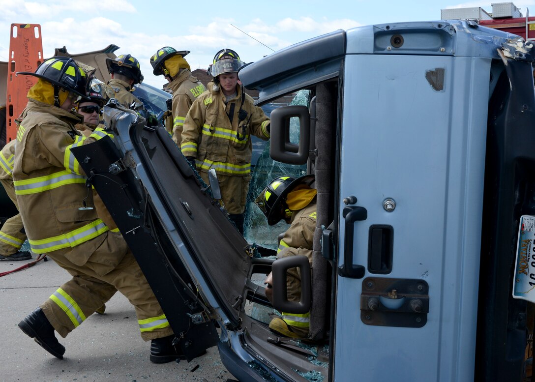 Firefighters from the South Dakota Army National Guard’s 451st Engineer Detachment and Ellsworth’s 28th Civil Engineer Squadron work together to remove the roof of a simulated crashed vehicle during a vehicle extrication training at Ellsworth Air Force Base, S.D., June 12, 2014. The training was part of this year’s Golden Coyote Exercise, providing firsthand experience with the tools and techniques needed to safely remove a victim from a vehicle accident. (U.S. Air Force photo by Senior Airman Anania Tekurio/Released)