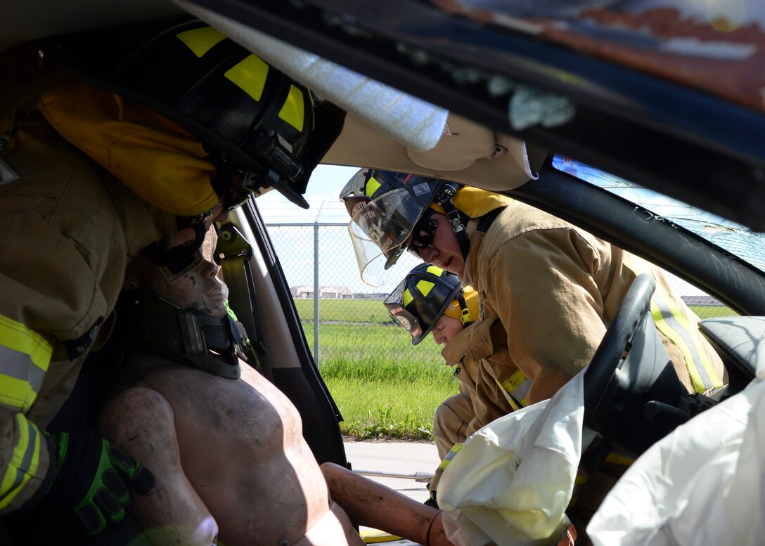 Firefighters from the South Dakota Army National Guard 451st Engineer Detachment practice rescuing victims from a major vehicle accident during vehicle extrication training as part of a Golden Coyote Exercise at Ellsworth Air Force Base, S.D., June 12, 2014. The training results will help assess the life-saving skills of firefighters involved in the training exercise. (U.S. Air Force photo by Senior Airman Anania Tekurio/Released)