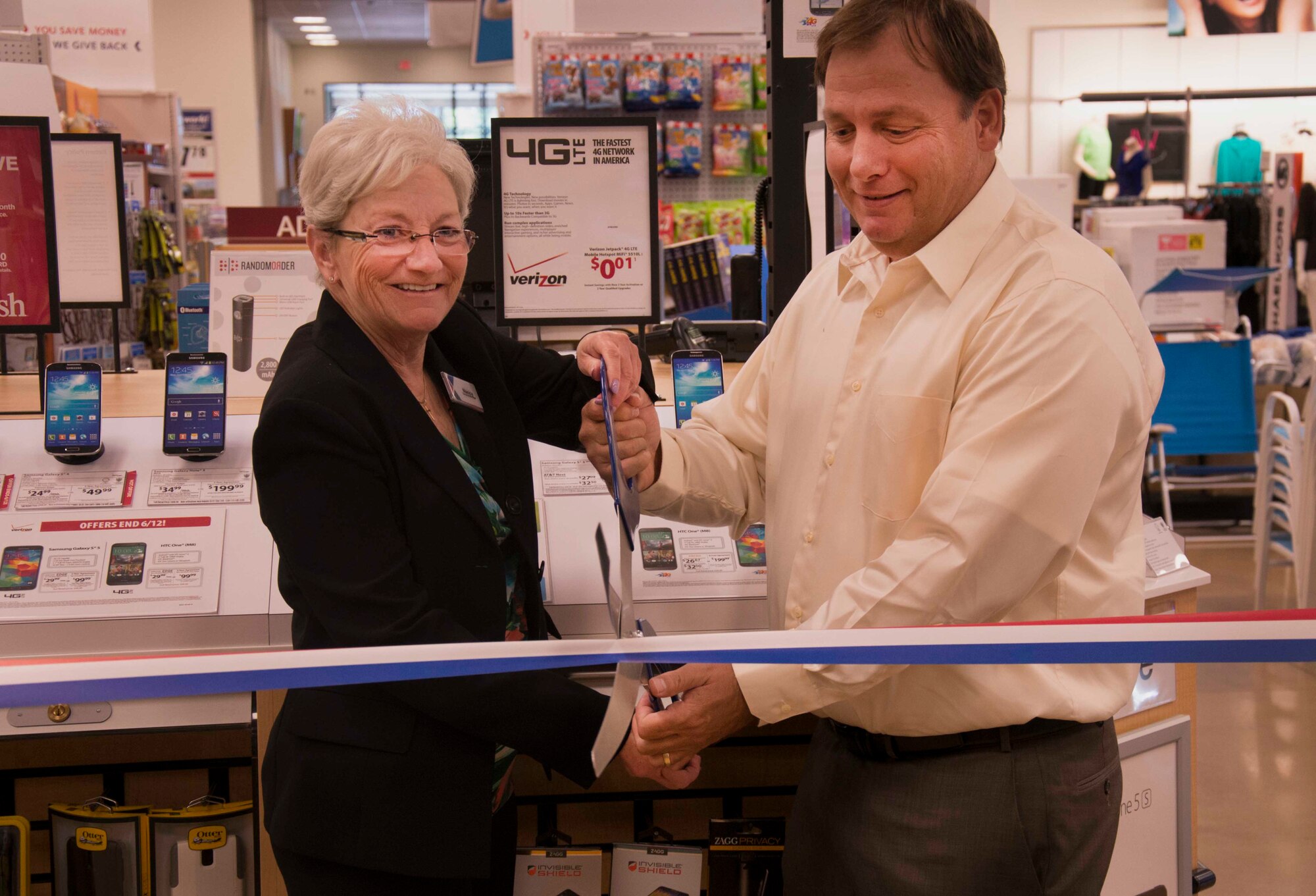 Base Exchange general manager Nancy Popada and Wireless Advocates district manager Bill Doty cut the ribbon during the grand opening of the Base Exchange mobile kiosk at Minot Air Force Base, N.D., June 12, 2014. The conveniently located kiosk will provide Airmen and their families on base with cell phone service and data plans without the commute to downtown Minot. (U.S. Air Force photo/Airman 1st Class Lauren Pitts) 