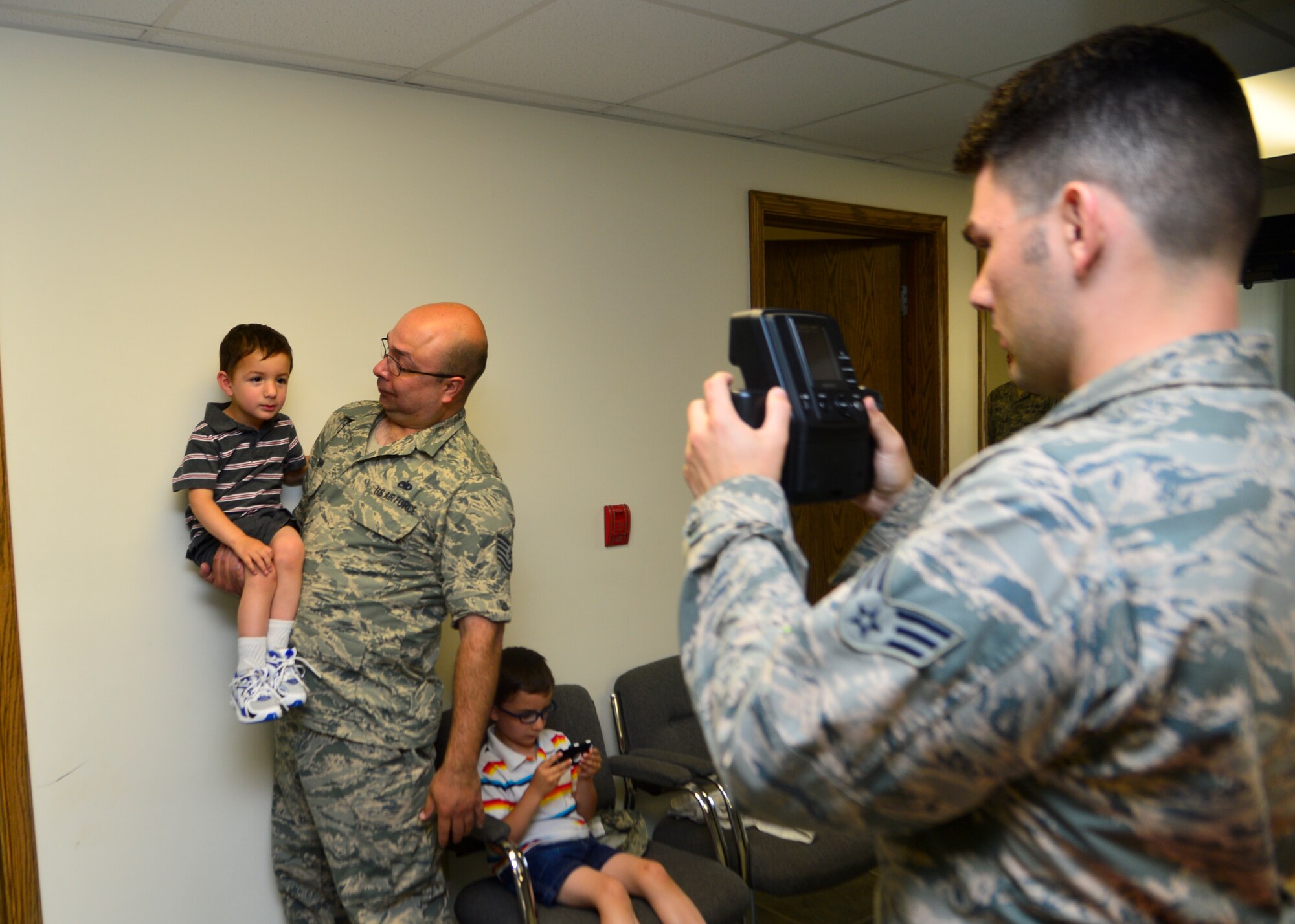 Senior Airman Jared Duhon, 436th Airlift Wing Public Affairs photojournalist, takes a passport photo of Xavian Dunn, son of Tech. Sgt. Gabriel Dunn, 736th Aircraft Maintenance Squadron programs coordinator, June 17, 2014, at Dover Air Force Base, Del. The wing’s public affairs office offers passport and visa photos for family members who are scheduled to leave the country for official travel. (U.S. Air Force photo/Airman 1st Class William Johnson)