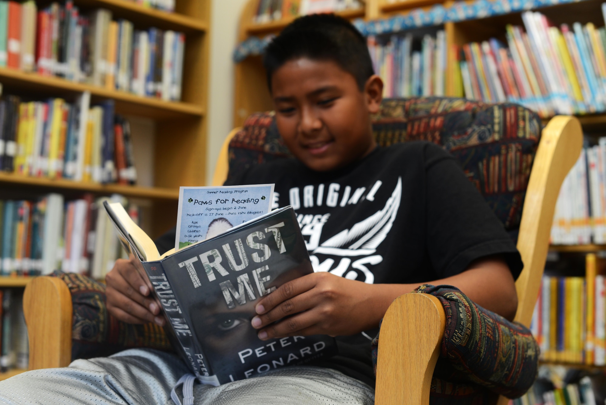 Jiles Masiclat, son of Tech. Sgt. Michael Clifford, reads a book at the library, June 17, 2014, at Aviano Air Base, Italy.  Throughout the summer, the Aviano Base Library offers various events to Airmen and family members, to include Story Time and a military working dog demonstration in support of the “Paws to Read” summer reading program. (U.S. Air Force photo/Airman 1st Class Deana Heitzman)