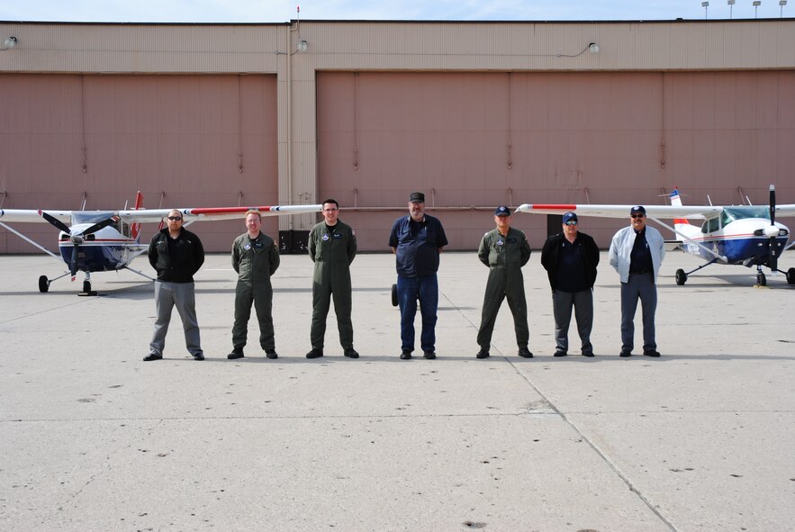 Situated between two Civil Air Patrol aircraft parked on the flightline of Grand Forks Air Force Base, N.D., on June 14, 2014, Capt. Daniel Villas, 1st Lt. Eric Jacobs and 2nd Lt. Graham Frost, from the 119th Air National Guard Cadet Squadron in Fargo, N.D., pose for a group photo with Gregory Weber, Kenneth Kudrna and Lt. Col. Ray Thompson from the Rough Rider Composite Squadron in Dickinson, N.D., along with retired Master Sgt. Al Vecchio, North Dakota CAP Wing deputy safety officer. The CAP members made their way to Grand Forks AFB in order to take part in the 2014 M.A.C.A. Civil Fly-In. Even though all the gentlemen are members of the North Dakota CAP, many of them had never met before. The civil fly-in provided the CAP members to get to know one another. (U.S. Air Force photo/Staff Sgt. Luis Loza Gutierrez)