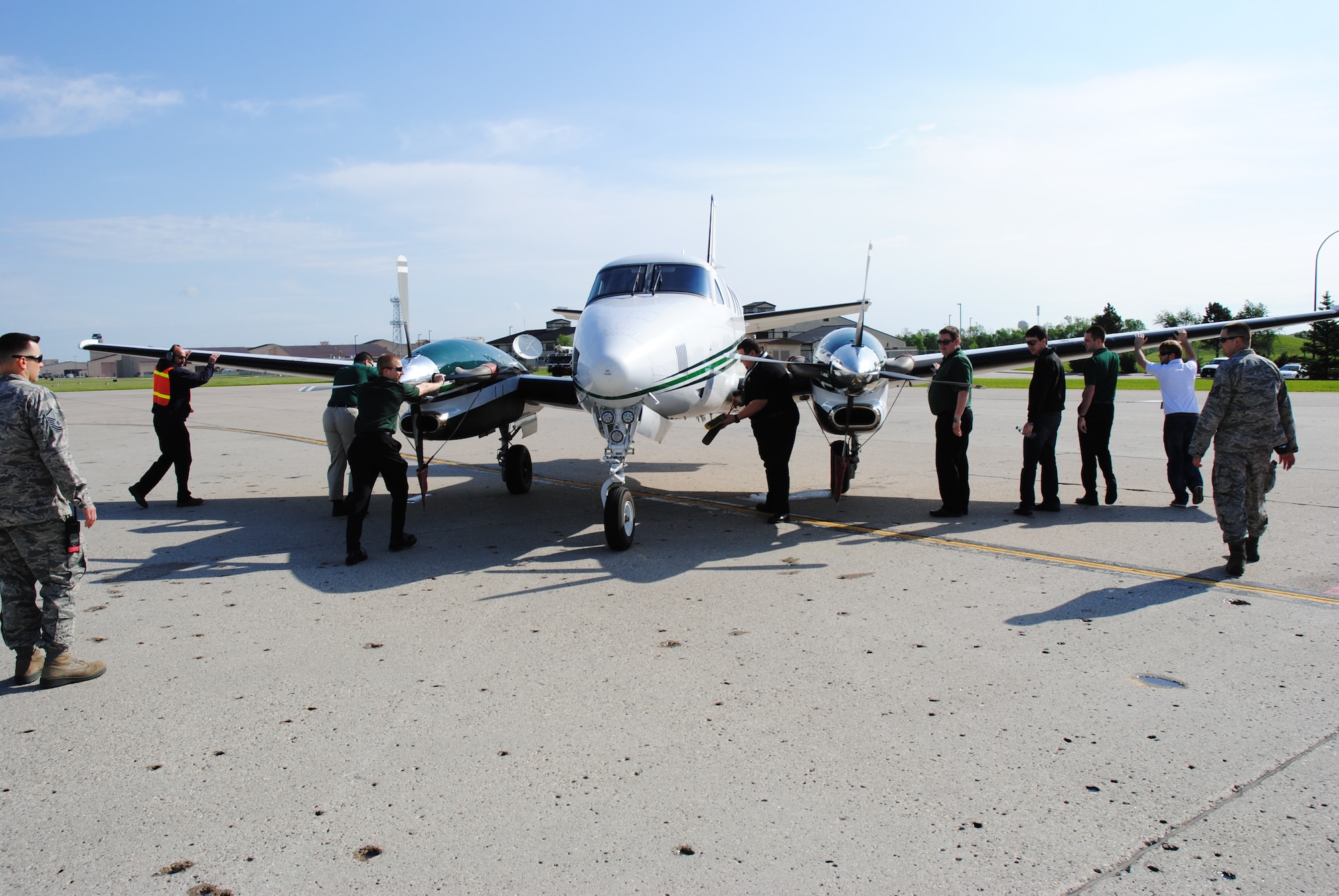 Members of the University of North Dakota Aerospace program push a Beechcraft King Air C90GTi back to the yellow line next to the Crouse Operations Center on June 14, 2014. The UND group were among 55 people who flew or drove into Grand Forks Air Force Base, N.D., in order to attend the 2014 M.A.C.A. Civil Fly-In.(U.S. Air Force photo/Staff Sgt. Luis Loza Gutierrez)