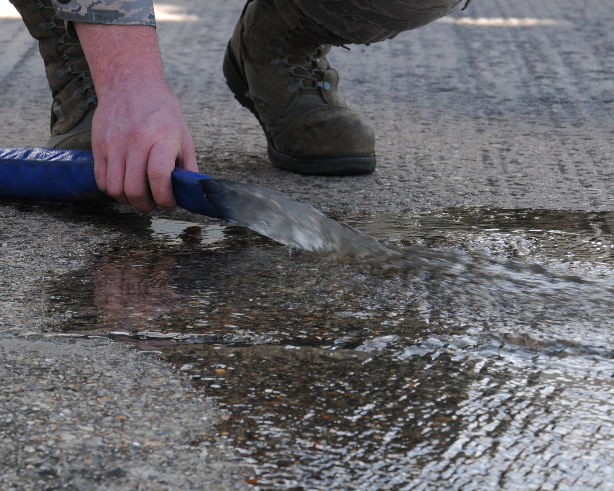 U.S. Air Force Staff Sgt. Ryin Rader, 100th Logistics Readiness Squadron NCO in charge of equipment support from Keyser, W.Va., places a hose during a wash rack drain clean June 13, 2014, on RAF Mildenhall, England. Within the wash rack system, 100th LRS personnel have a water-recycling system to reuse water from the initial rinse on a government vehicle and use the same water to rinse it off after it has been washed. This is one way the 100th LRS aims to save the base money by cutting water costs. (U.S. Air Force photo/Gina Randall/Released)
