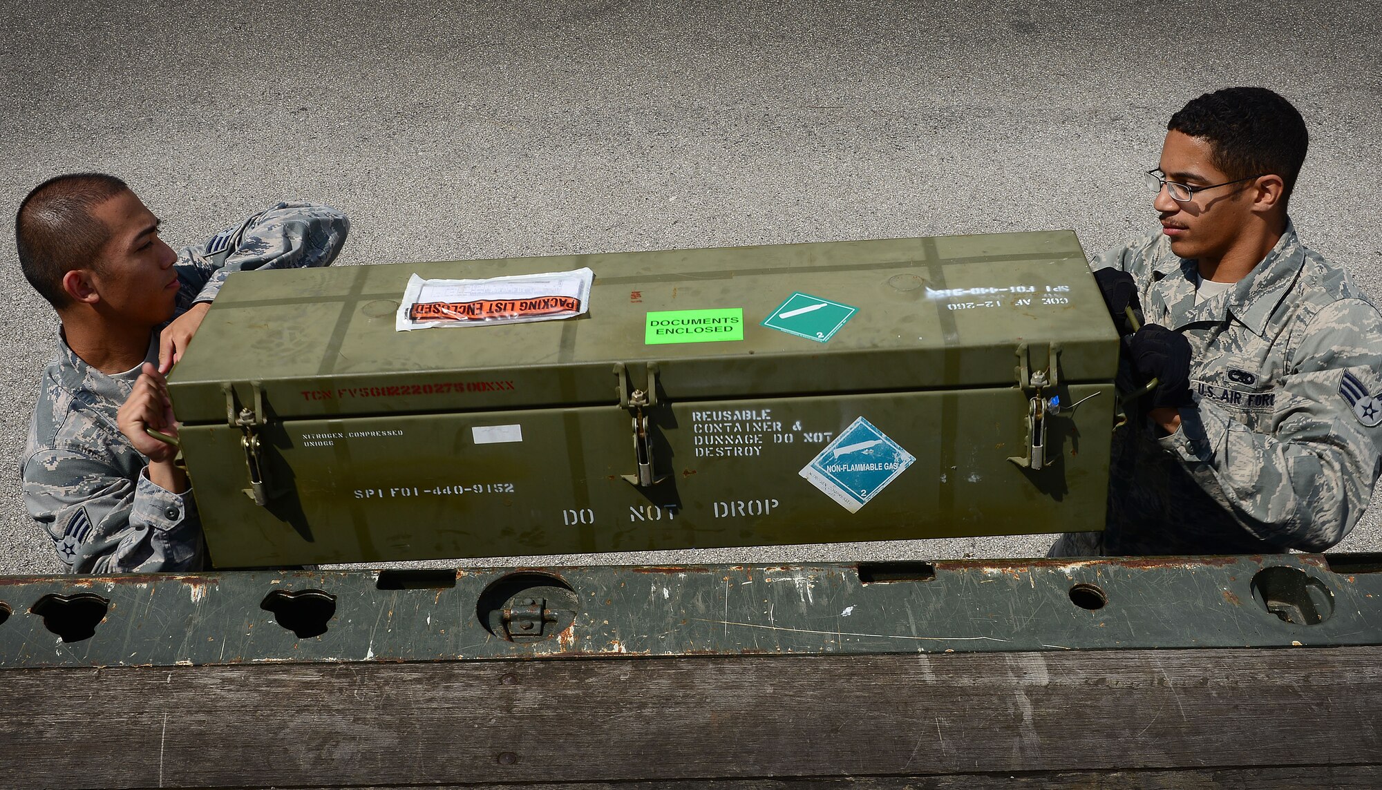 (From left) Senior Airmen Gerald Gutierrez and Joseph Carlyon pick up a munitions box, June 16, 2014, at Aviano Air Base, Italy. The storage section pulls the necessary munitions and coordinates transportation between geographically-separated locations with agencies such as security forces, Italian security forces and carabinieri. Gutierrez and Carlyon are 31st Munitions Squadron storage crew members. (U.S. Air Force photo/Senior Airman Matthew Lotz)
