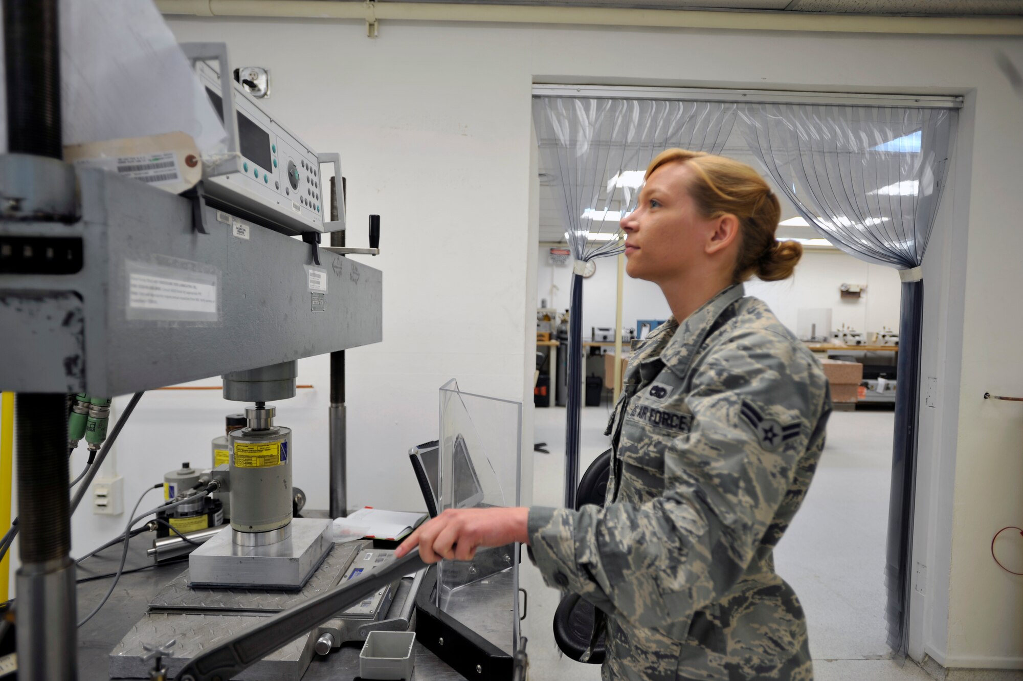 Airman 1st Class Diana LeGro, 51st Maintenance Squadron precision measurement equipment laboratory technician, uses a force press to generate 20,000 pounds of force to calibrate a wheel load scale on Osan Air Base, Republic of Korea, June 13, 2014. The wheel load scale is used to weigh vehicles, aircraft and cargo. (U.S. Air Force photo/Senior Airman David Owsianka)