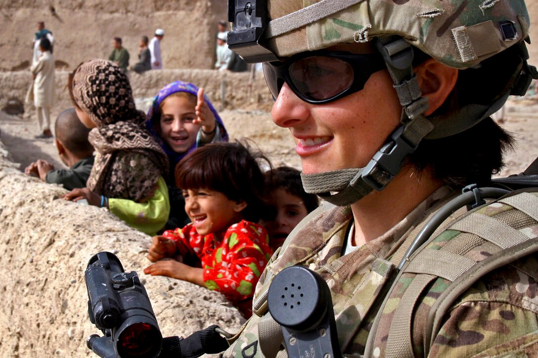 U.S. Army Pfc. Jessica Dostie rests against a wall before distributing gifts to the children behind her while on patrol in Kandahar, Afghanistan, Sept. 30, 2011. Dostie is a military policewoman assigned to the 4th Infantry Division's 58th Military Police Company, 2nd Brigade Combat Team. 
