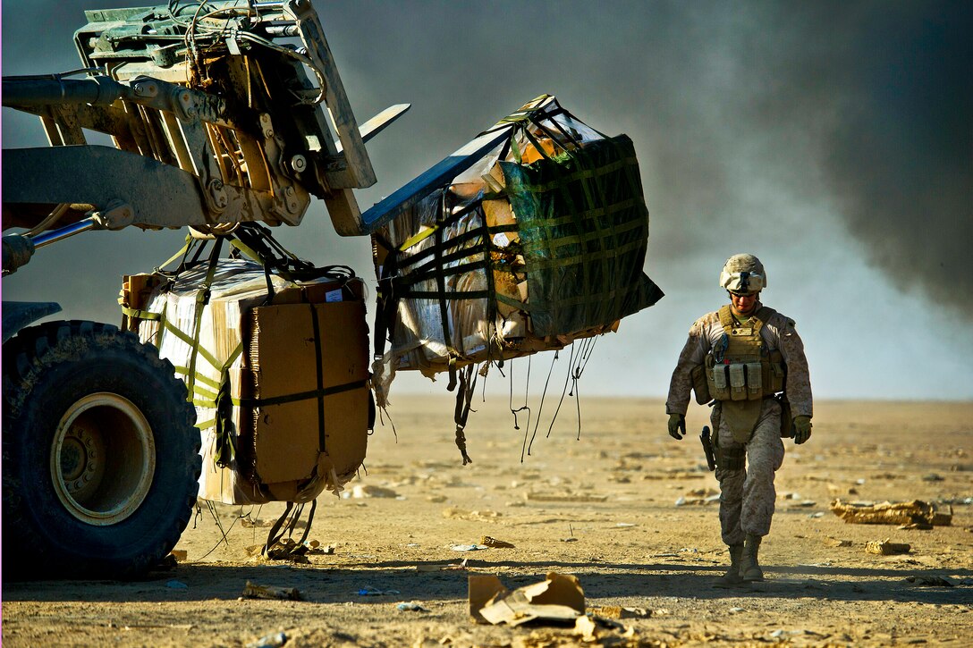 A U.S. Marine collects bundles of food rations airdropped to Forward Operating Base Edinburgh, the logistics hub for northern Helmand province, Afghanistan, Oct. 3, 2011. Troops burn the parachutes and other packing materials on site to reduce the debris left on the drop zone. Aerial delivery of food and water allows Marines to get some critical supplies without having to rely on risky ground convoys.  
