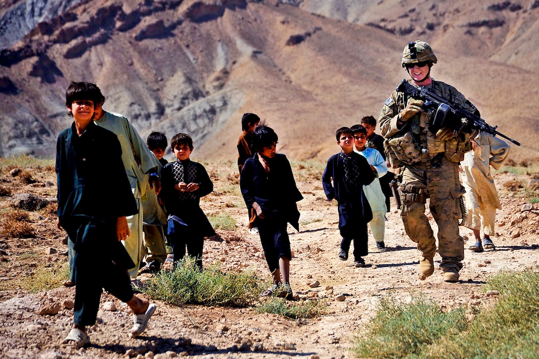 U.S. Army Spc. Michael Leone walks with Afghan kids while providing security on patrol in the Purchaman district in Afghanistan's Farah province, Sept. 26, 2011. Leone is assigned to Company C, 1st Battalion, 182 Infantry Regiment, security force for Provincial Reconstruction Team Farah. The team attends shuras throughout the province to demonstrate support for the shura elders, the district governor and provincial governance.  
