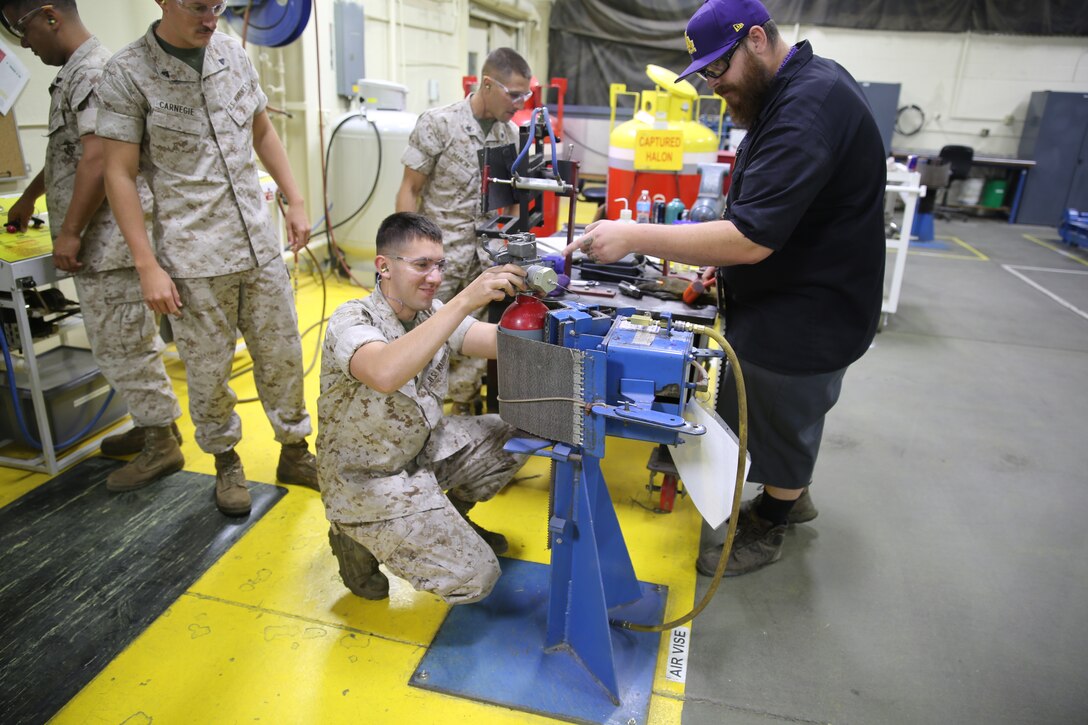 Staff Sergeant Kevin Jones, Corporals Samuel Harney, Zach Carnegie, Jonathan Manciniand, Lance Cpls. Michael Solis, and Chandler Bird, worked hands-on with mechanics from Production Plant Barstow, Marine Depot Maintenance Command on Marine Corps Logistics Base Barstow, Calif., from May 22 to May 30. Arthur Gutierrez, hydraulics system mechanic and Luke Wirick, heavy mobile equipment mechanic, trained and certified the Marines to fill discharge, and test automatic fire suppression systems (AFSS).