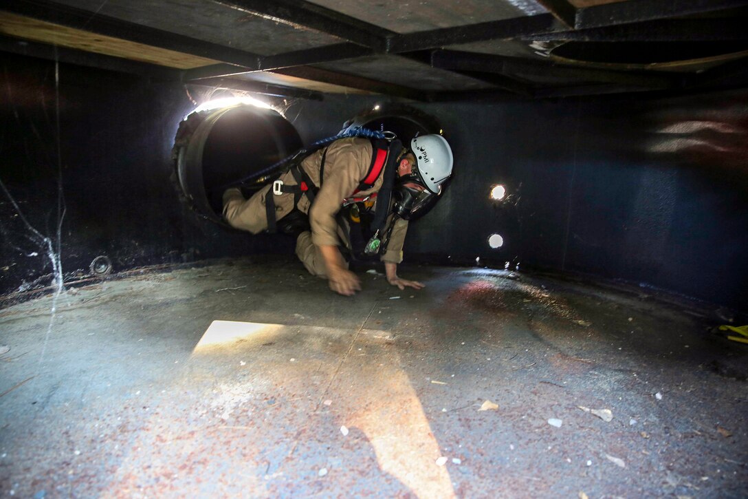 Corporal Dustin Clayton, an aircraft rescue and firefighting specialist, crawls through the confined space simulator at Pinewood Station 894 in Burton, S.C., June 10. The confined space simulator is designed to train firefighter to function calmly in small spaces.