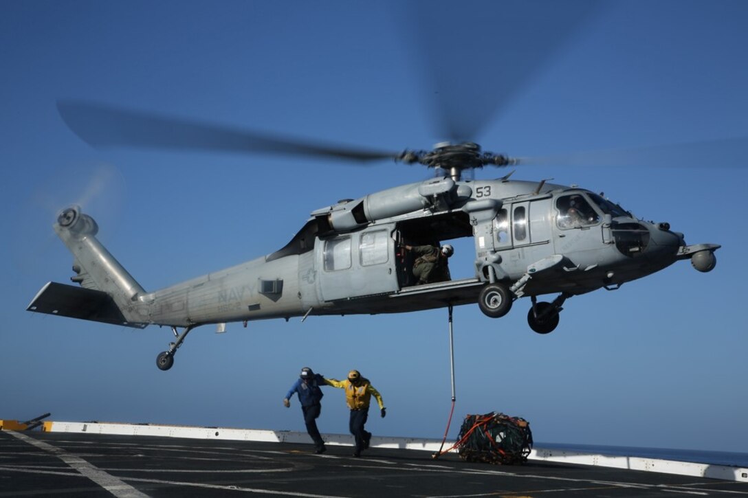 Sailors with the USS San Diego air department move off the flight deck after hooking a cargo pallet on an MH-60S Sea Hawk with Helicopter Sea Combat Squadron 23 (HSC-23) as part of a vertical replenishment exercise from the flight deck during Certification Exercise (CERTEX) off the coast of Southern California, June 18, 2014. CERTEX is comprised of a specific series of missions intended to evaluate and certify the 11th Marine Expeditionary Unit for their upcoming deployment with the Makin Island Amphibious Ready Group scheduled for later this summer. (U.S. Marine Corps photo by Cpl. Jonathan R. Waldman/RELEASED)