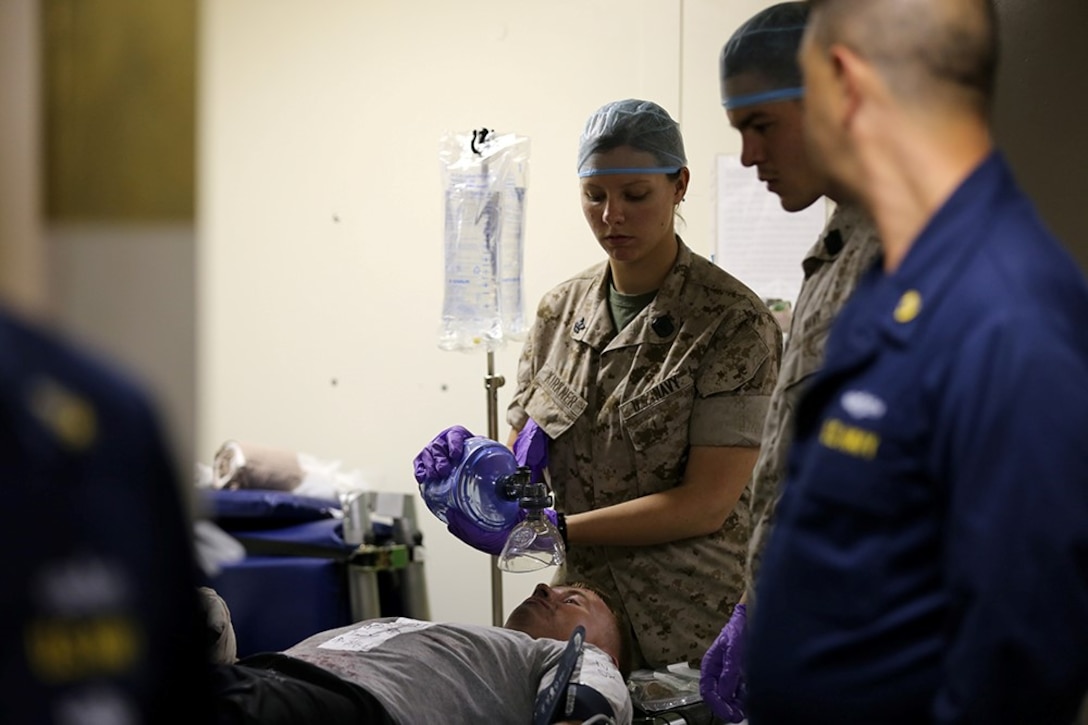 A corpsman, center, with the 11th Marine Expeditionary Unit, provides medical assistance to a simulated injured role player in the main battle dressing station of the USS San Diego as part of a mass casualty drill conducted during Certification Exercise (CERTEX) off the coast of Southern California, June 14, 2014. The 11th MEU and Amphibious Squadron 5 team conducts CERTEX to hone mission-essential tasks, execute specified MEU and Amphibious Ready Group operations, and certify the foundation of a cohesive warfighting team for exercises and operations they may encounter in their upcoming deployment. (U.S. Marine Corps photo by Gunnery Sgt. Rome M. Lazarus/Released)