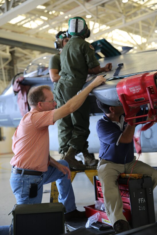 Two aviation electricians work on the top of the wing on an AV-8B Harrier while two Boeing field service representatives work on the underside of the wing during routine maintenance on the bird in the Marine Attack Squadron 542 hangar. Boeing FSRs act as mentors to Marines in areas like avionics, airframes, power line, crew safety systems and supply.
